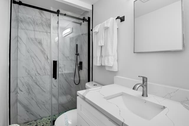 Bright bathroom with walk-in shower and fresh towels provided.