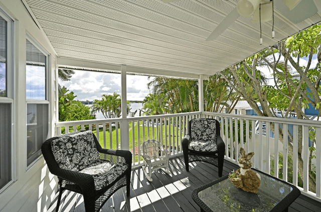 Relax in your private covered balcony with comfortable wicker seating and peaceful water views through tropical foliage.