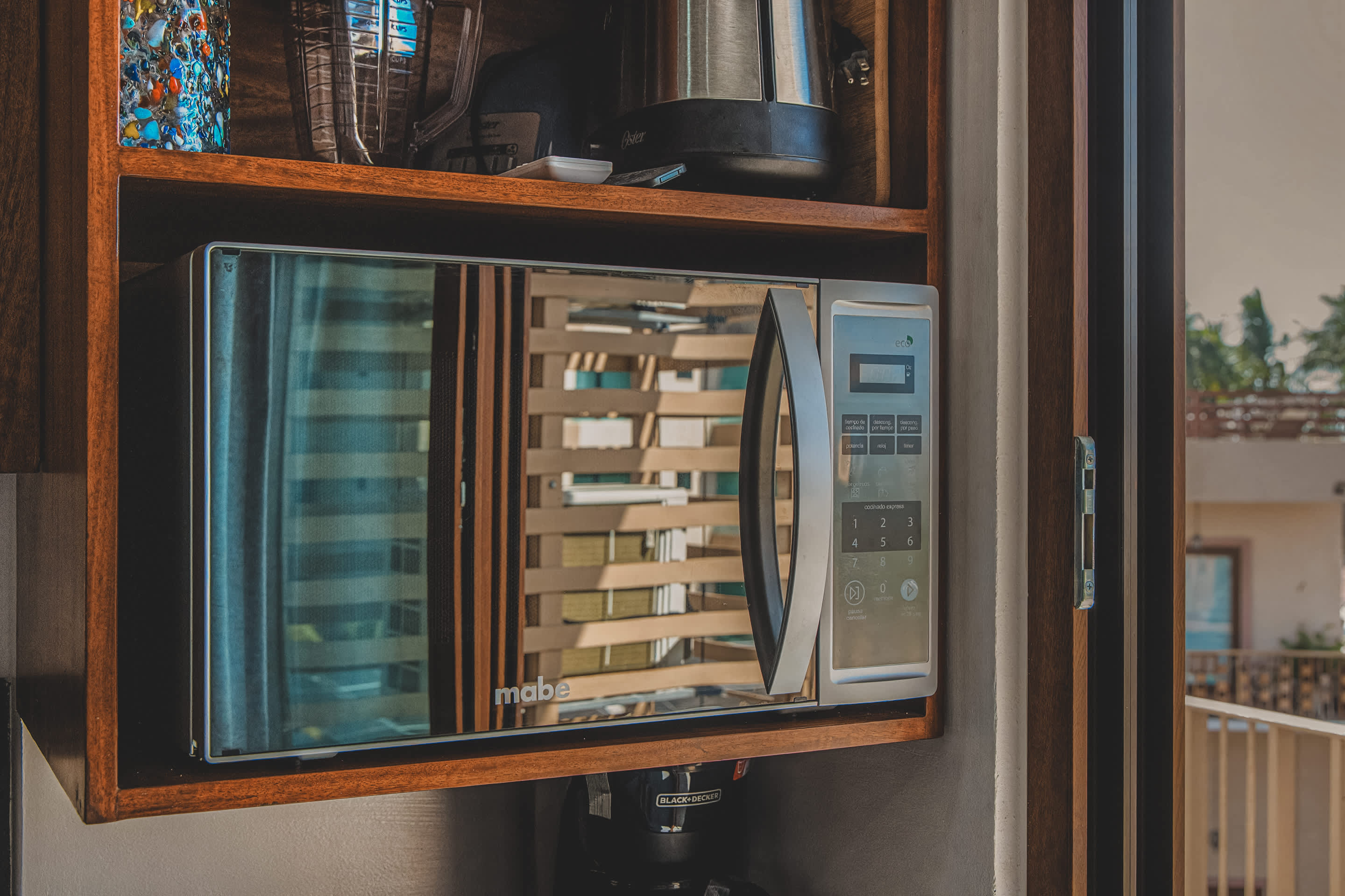 Built-in stainless steel Mabe microwave oven with a reflective door, housed within a wooden cabinet.