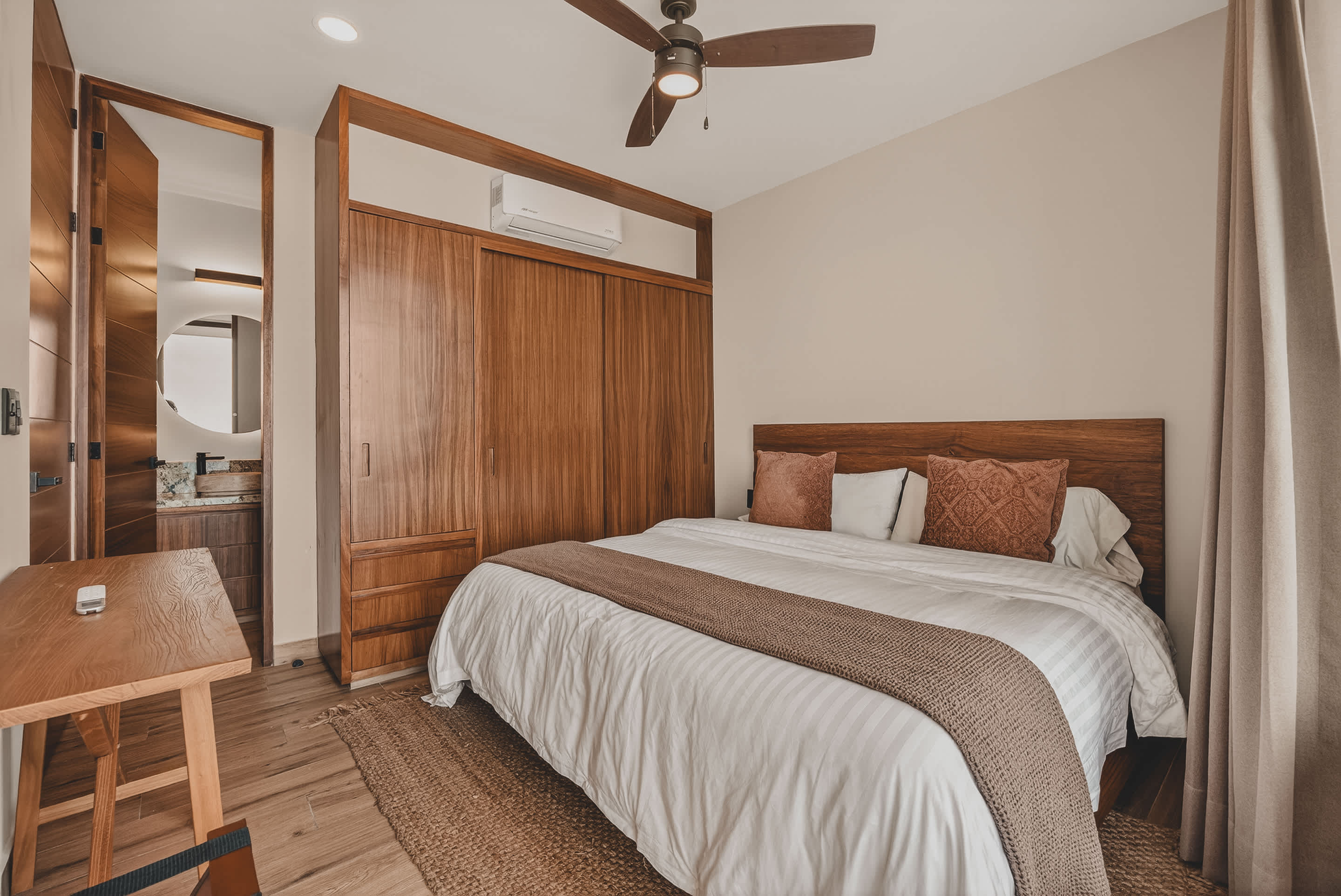 Cozy bedroom-2 with a king-size bed, wooden headboard, and built-in wooden wardrobe, with a glimpse of the en-suite bathroom through an open doorway.