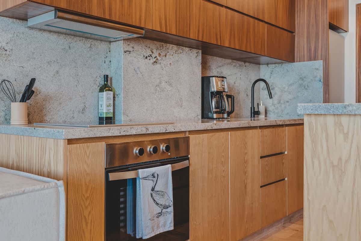 A well-equipped kitchen showcases light wood cabinetry, granite countertops, a built-in oven with a pelican-themed towel, and a coffee maker, providing a functional and stylish cooking space.