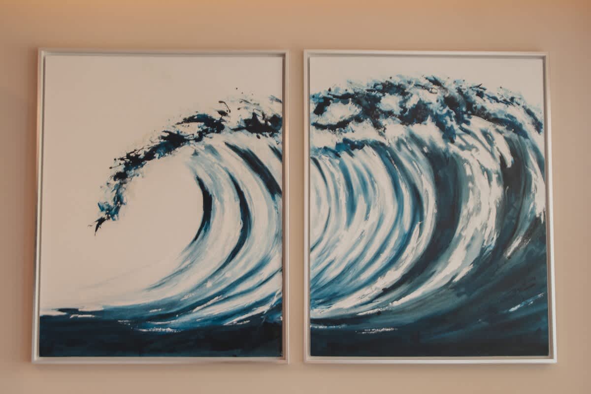 Two framed artworks depicting dynamic blue and white ocean waves, adding a vibrant coastal theme to the room's decor.