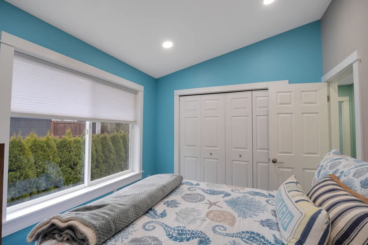 Another view of the bedroom, highlighting the blue accent wall, the queen bed with themed bedding, and a white closet with bi-fold doors.