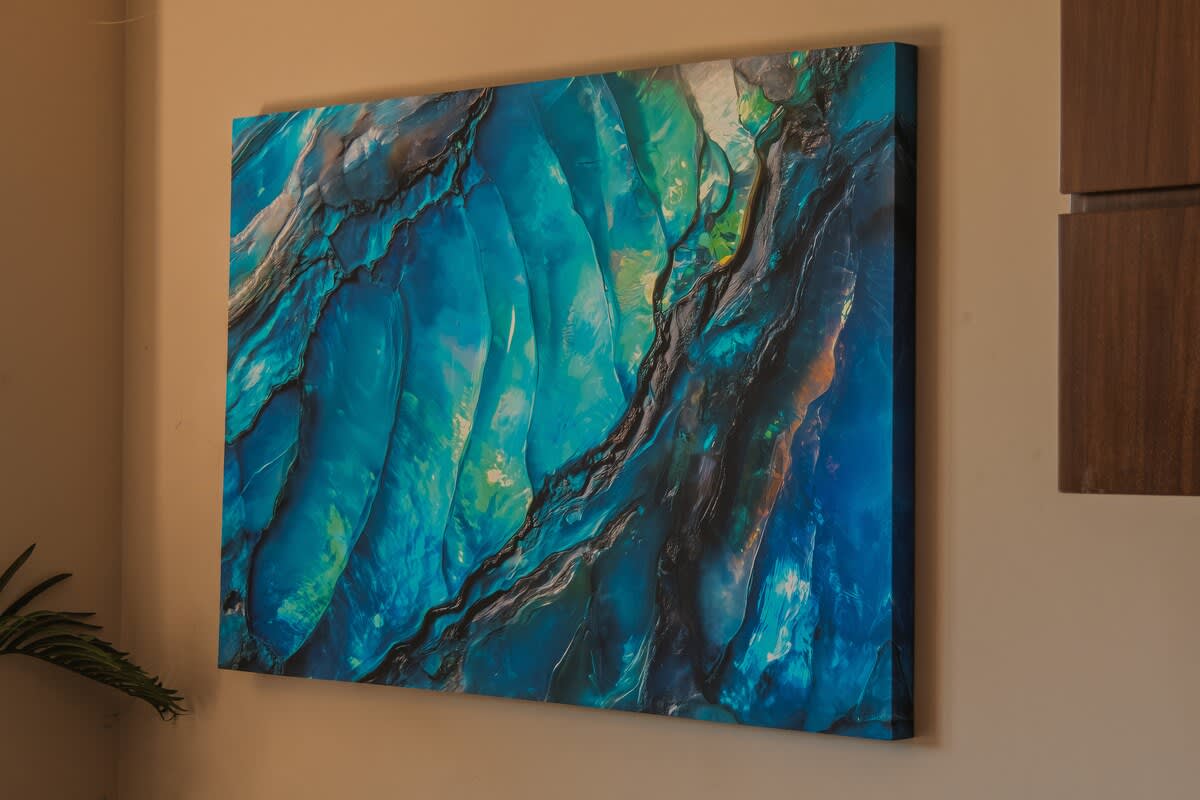 A vibrant, large-format canvas features an abstract artwork dominated by swirling shades of blue and green, with dark, textured lines creating a dynamic, organic pattern. The piece adds a modern and artistic touch to the interior space.