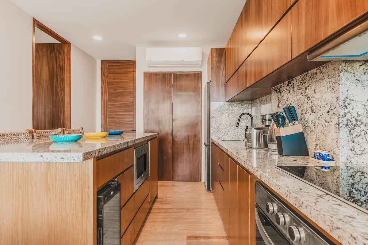 Well-appointed kitchen showcasing light wood flat-panel cabinetry, speckled granite countertops, a built-in oven, and a large integrated refrigerator, designed for both functionality and style.