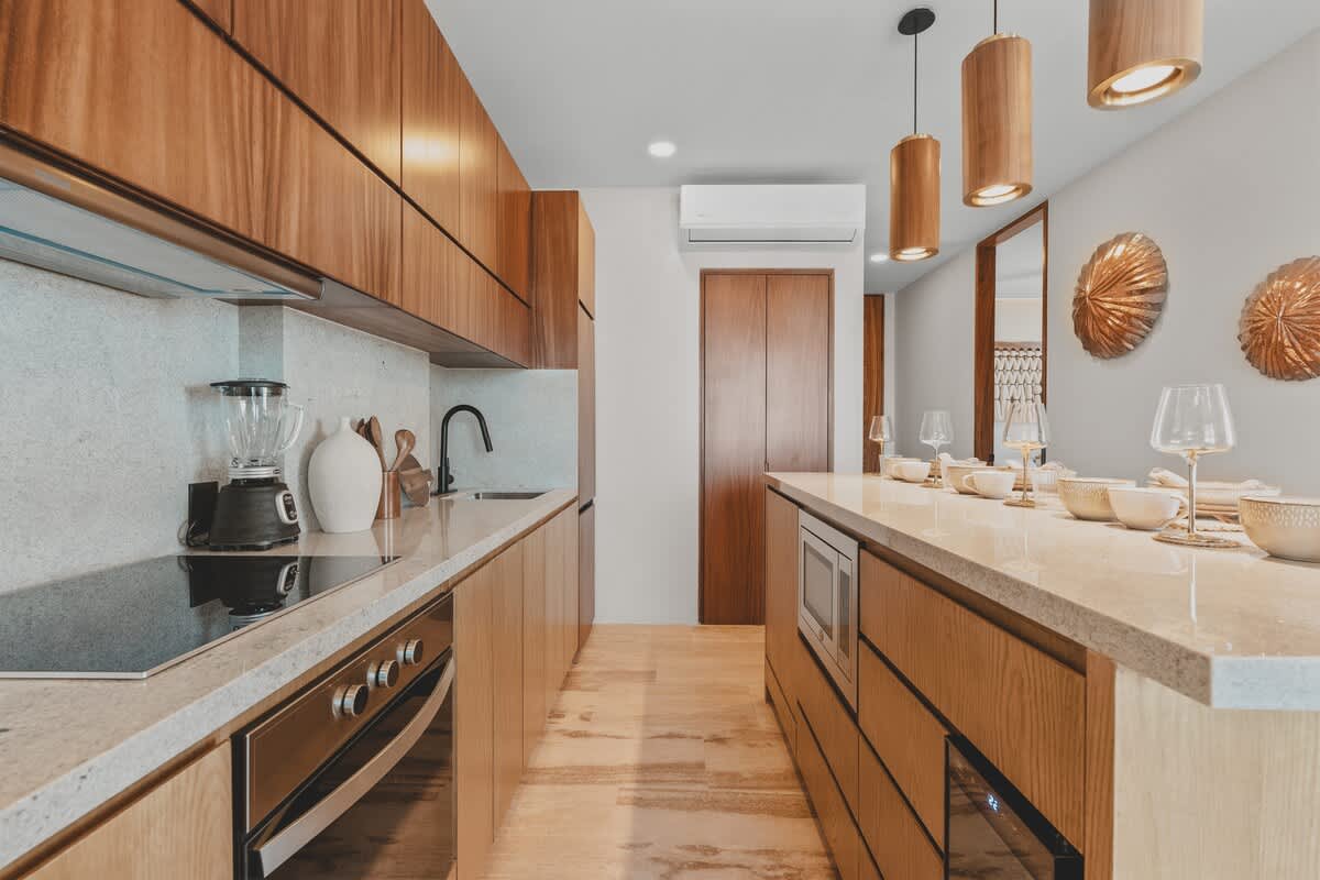 Modern kitchen with light wood lower cabinetry and dark wood upper cabinets, light speckled granite countertops, and stainless steel appliances including a built-in oven and induction cooktop.