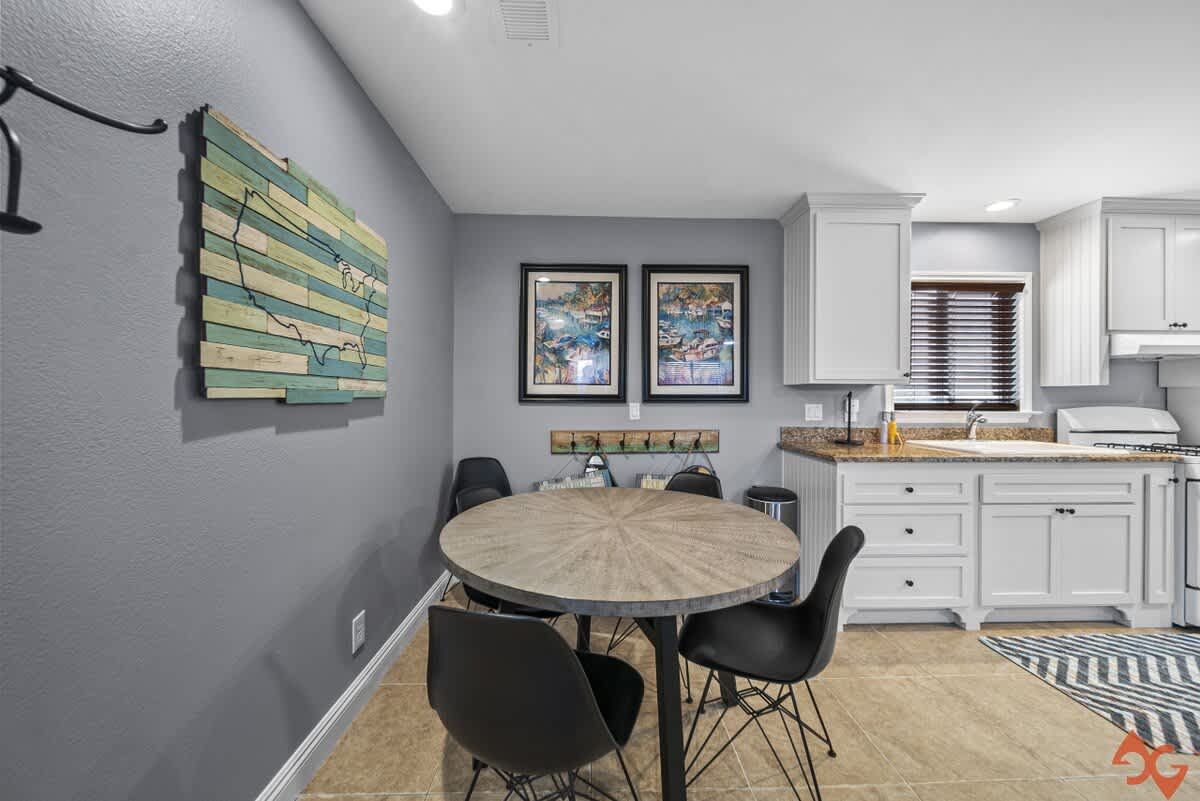 Cozy dining area with a round wooden table and four black modern chairs, set against a gray wall with a decorative wooden map of the USA.