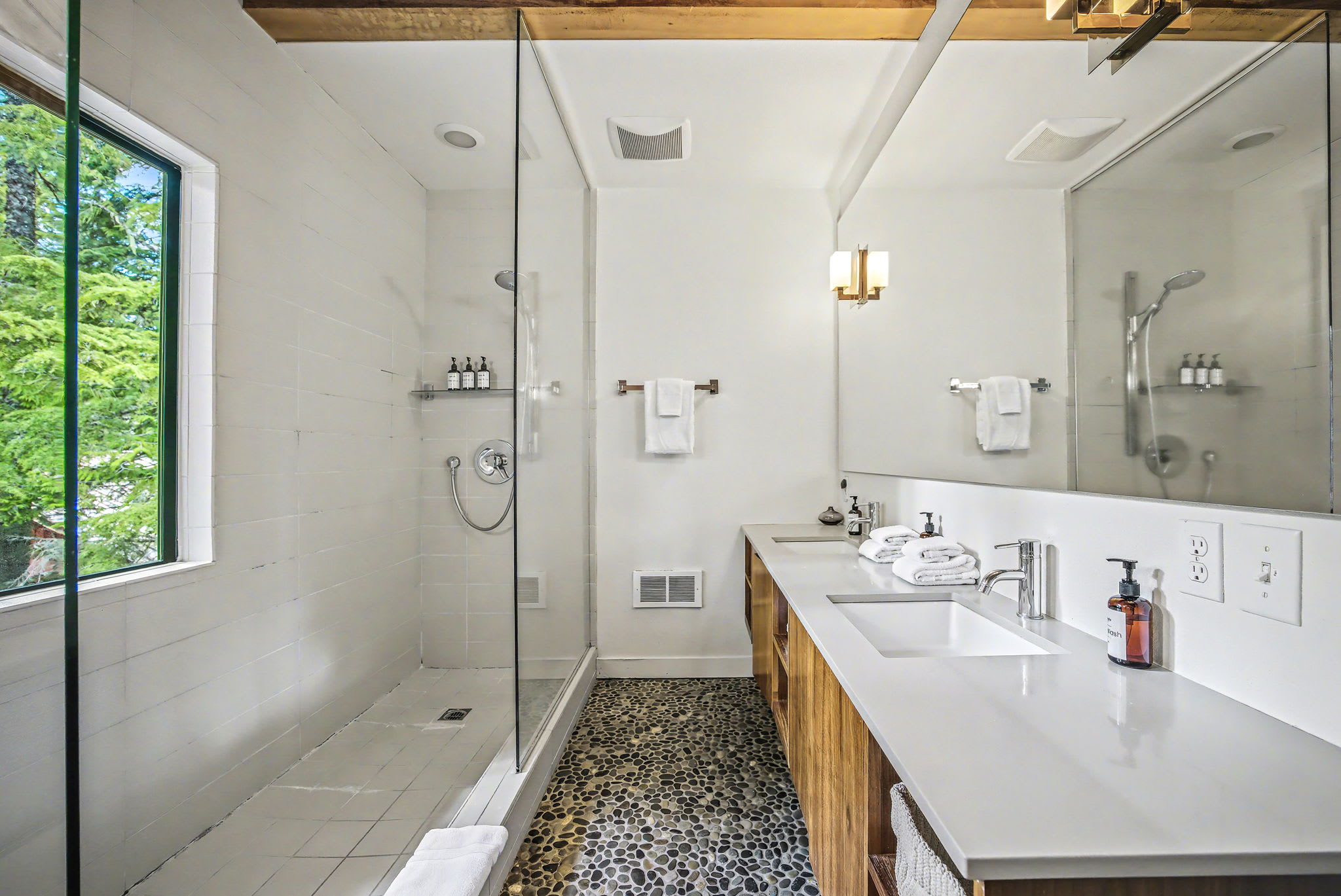 Another view of the attic bedroom, showing a cozy armchair and a small side table. The sloped ceiling with exposed wooden beams and a skylight are prominent features, adding to the rustic charm.