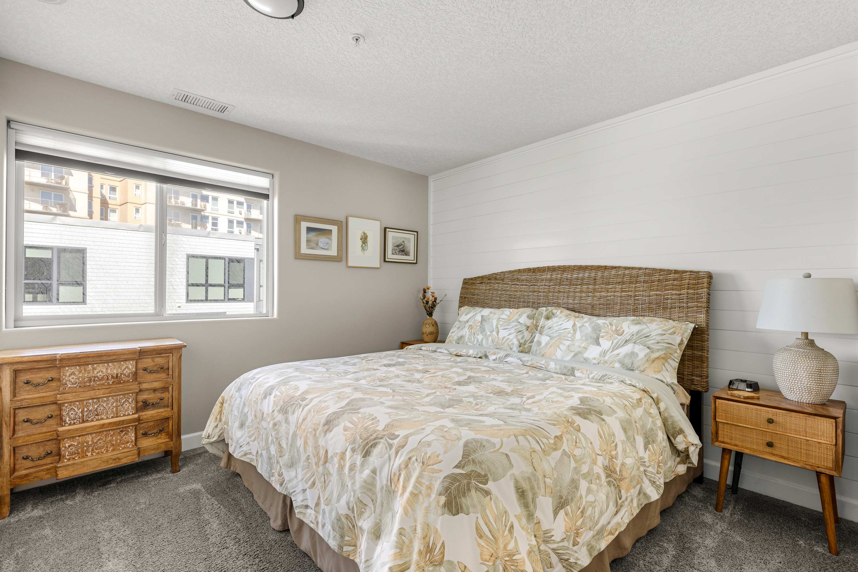 Spacious bedroom with a luxurious king bed, elegant wood furniture, and abundant natural light for a refined coastal stay.