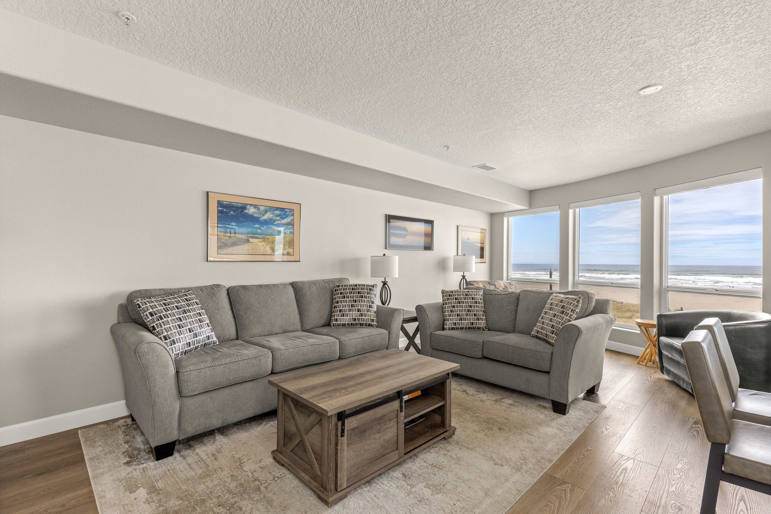 Relax in this open living room with ocean views, cozy seating, and a bright, airy coastal atmosphere.