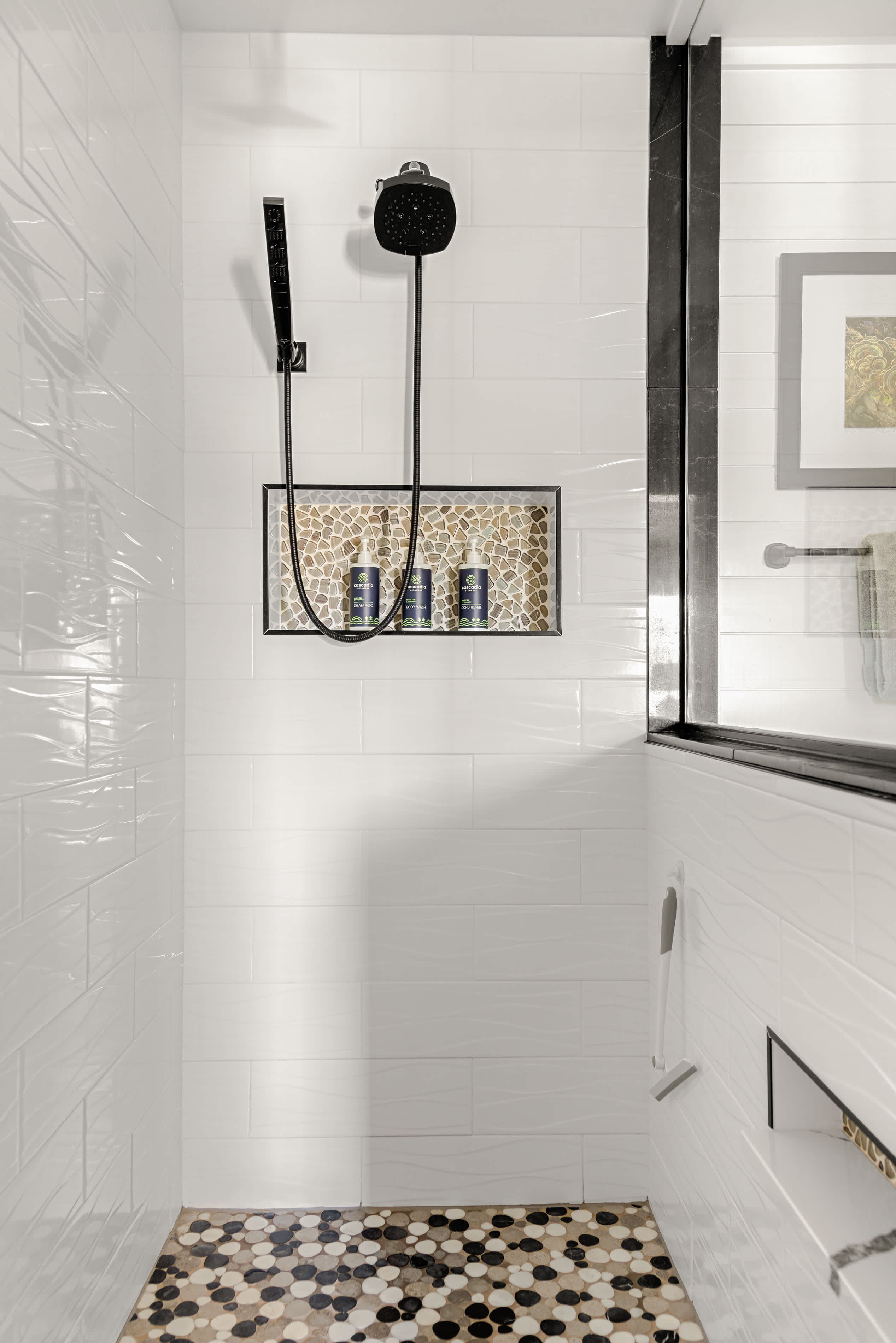 Walk-in shower with rainfall head, handheld sprayer, and built-in niche for convenience.