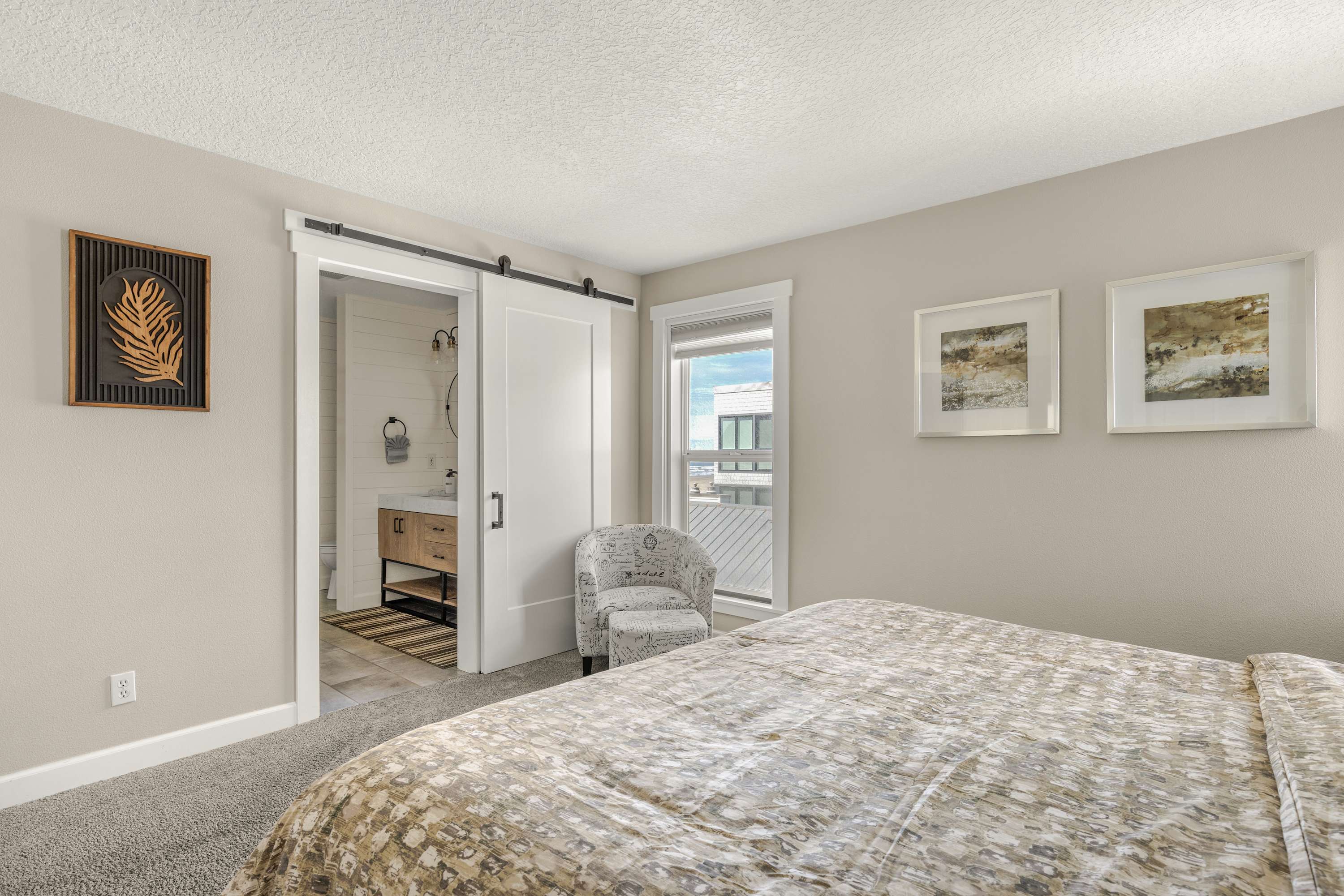 Primary bedroom with sliding barn door leading to a modern ensuite bathroom for added privacy and style.