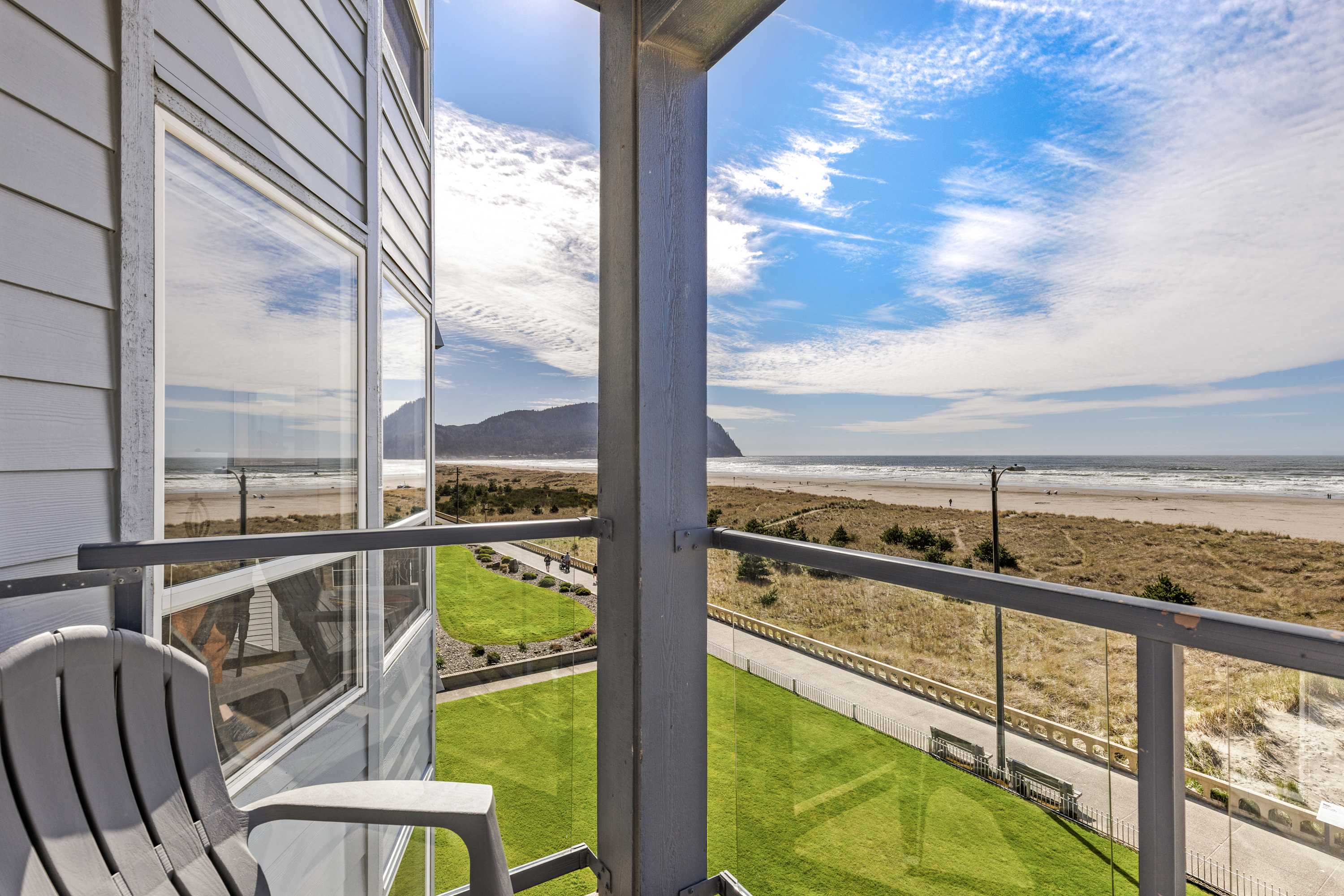 Relax on your balcony with panoramic views of the coastline, beach dunes, and scenic mountain horizon.