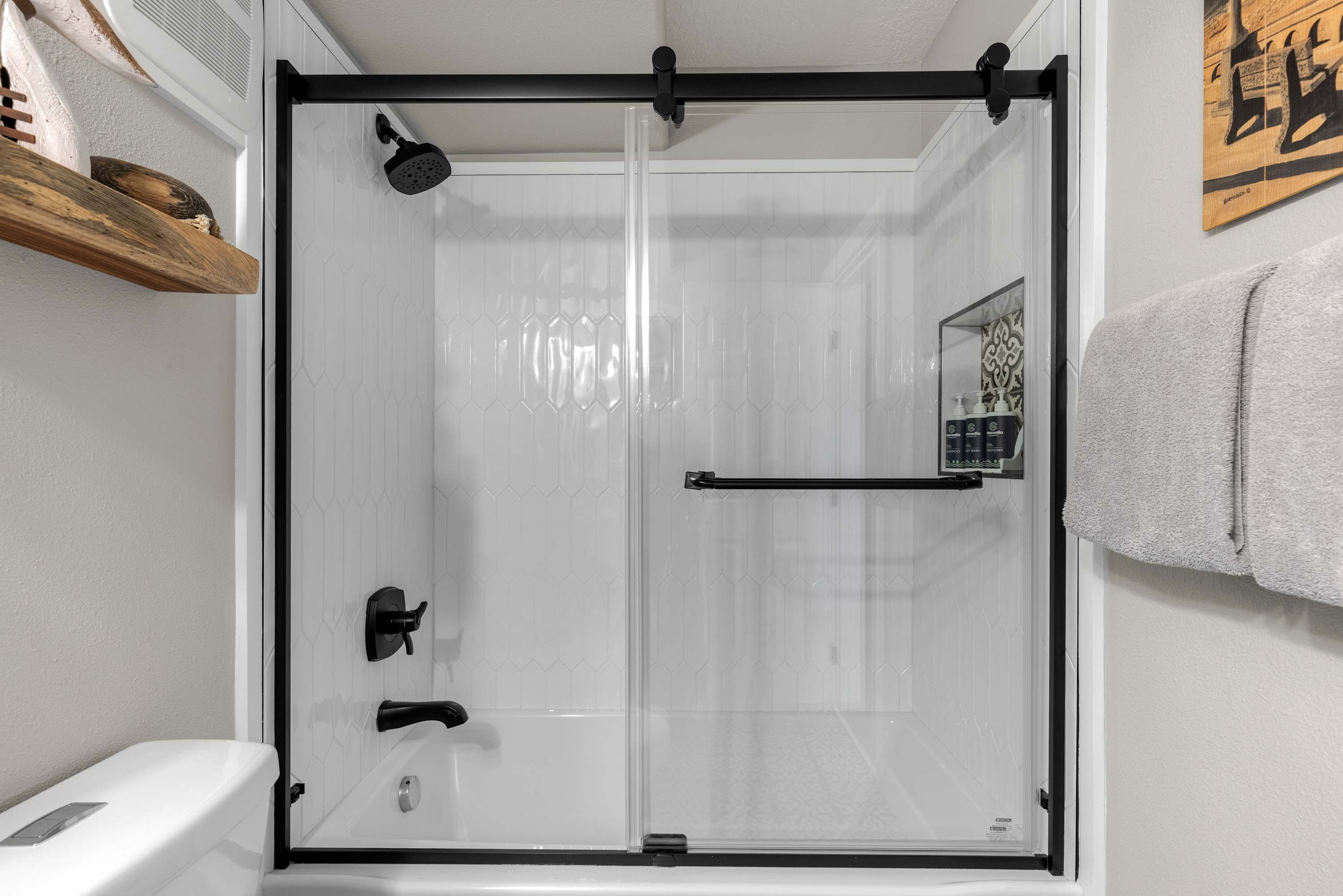 Modern bathroom with glass-enclosed shower, sleek black fixtures, and bright tile—perfect for a refreshing, spa-like stay.