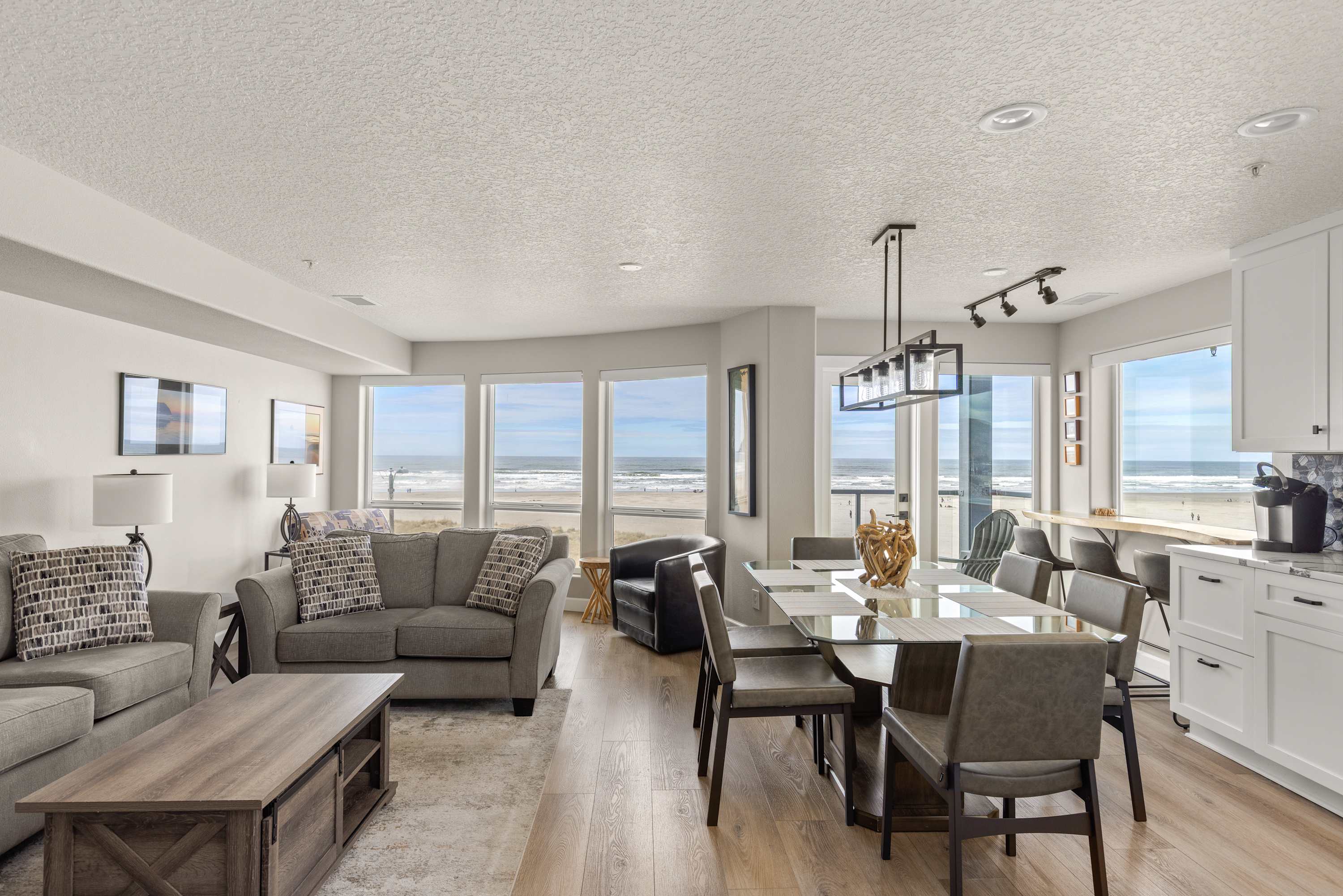 Stunning open-concept living and dining area with panoramic ocean views, modern furnishings, and bright coastal design—perfect for relaxing stays.