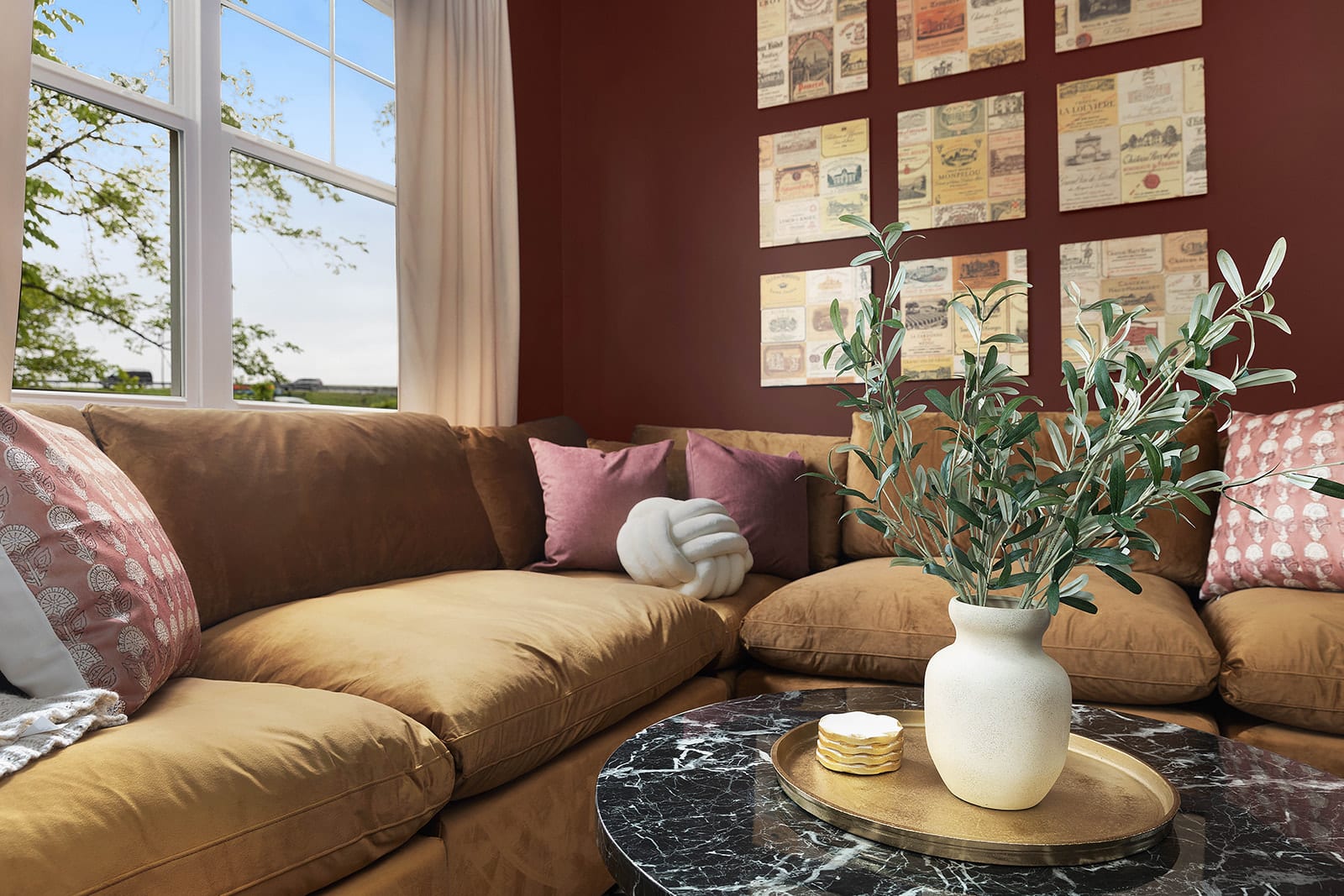 A close-up view of the plush brown sectional sofa in the living room, adorned with various throw pillows, centered around a black marble coffee table with a decorative vase and tray.