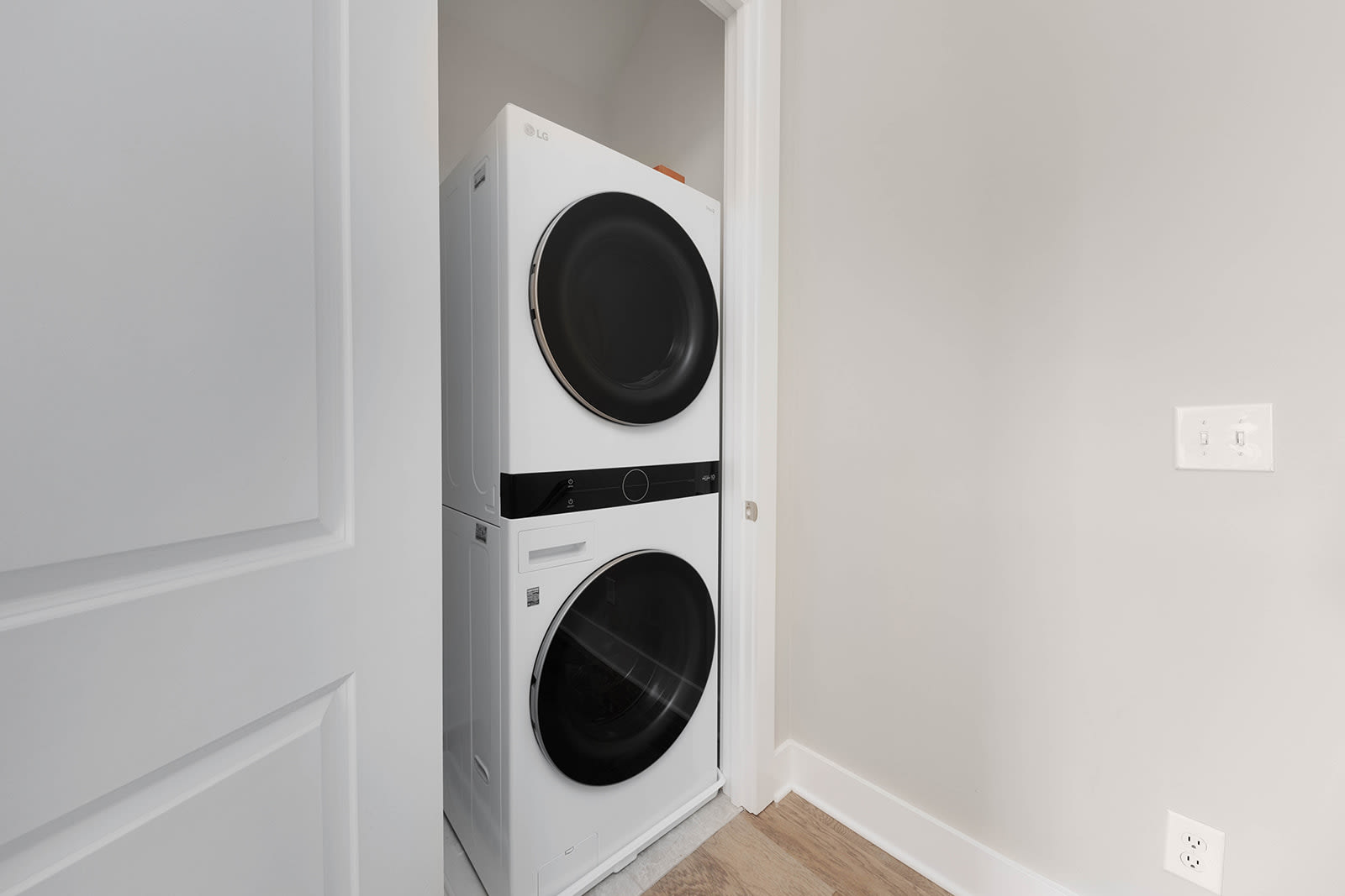 A compact laundry closet featuring a white stacked washer and dryer unit, set against light neutral walls. The space is functional and efficiently designed for laundry tasks.