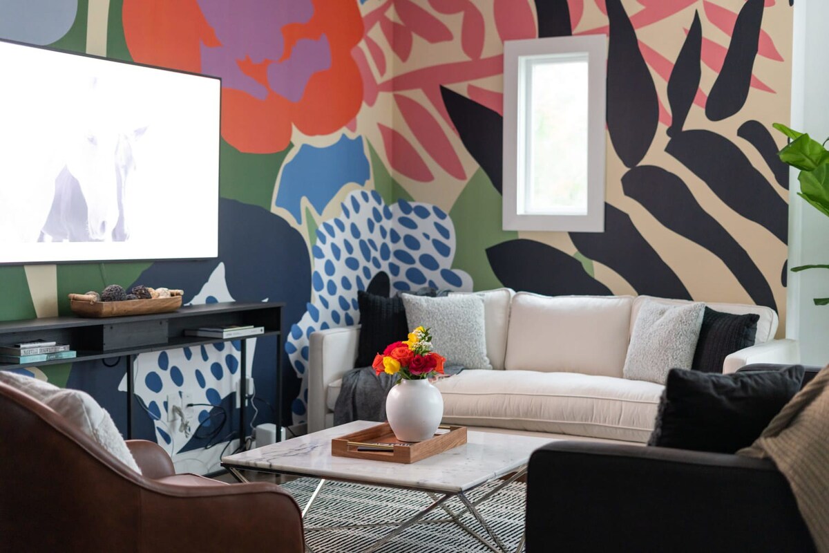 A close-up of the living room's seating area, highlighting the white sofa adorned with throw pillows, a brown leather accent chair, and a marble coffee table with a decorative tray and fresh flowers.