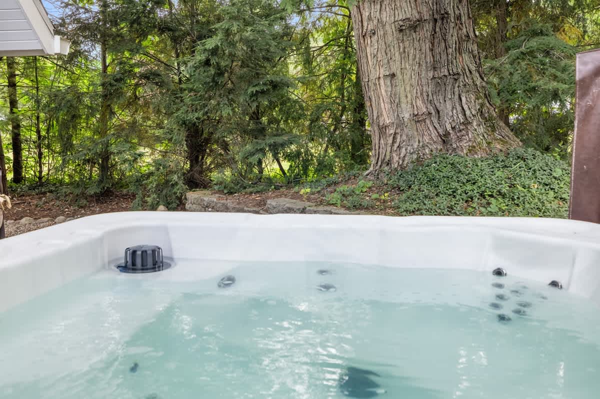 Close-up view of a clean, bubbling hot tub with visible jets, surrounded by natural stone and lush green foliage, offering a relaxing outdoor experience.