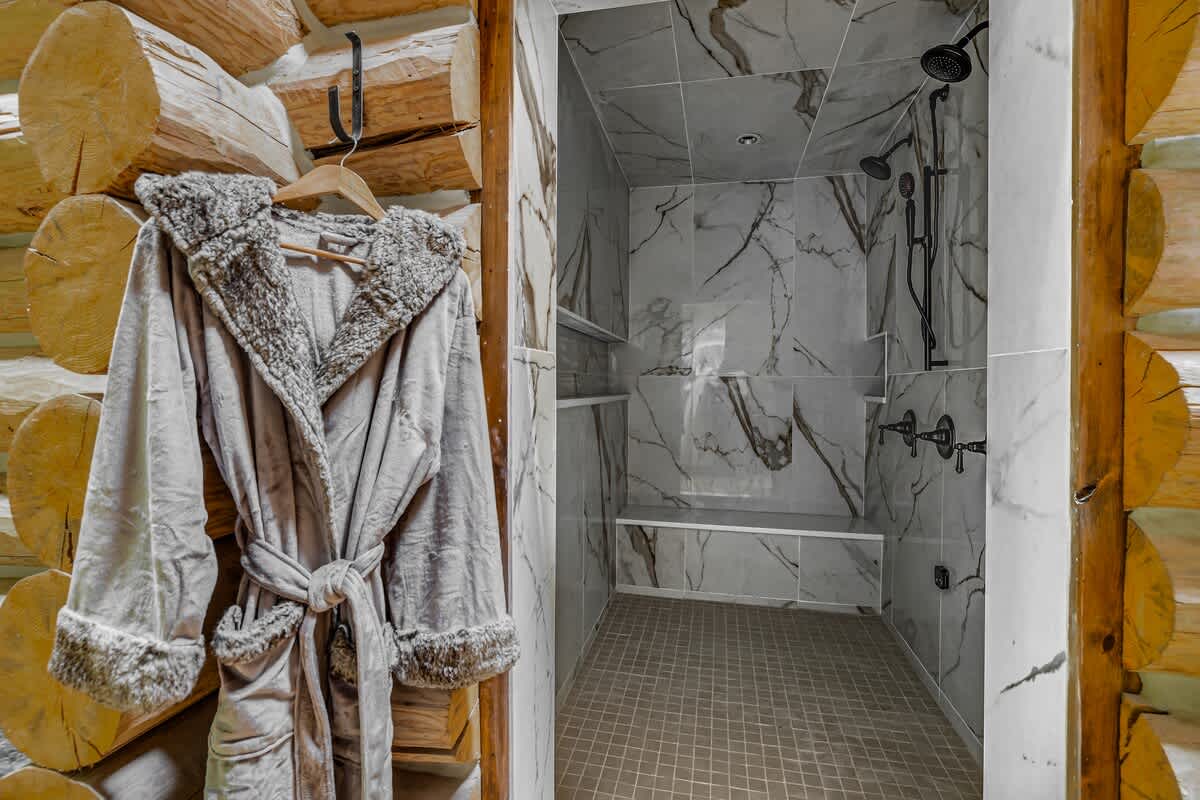 Modern walk-in shower with elegant marble-look tiles covering the walls and floor, equipped with a built-in bench and multiple shower heads, offering a luxurious bathing experience.