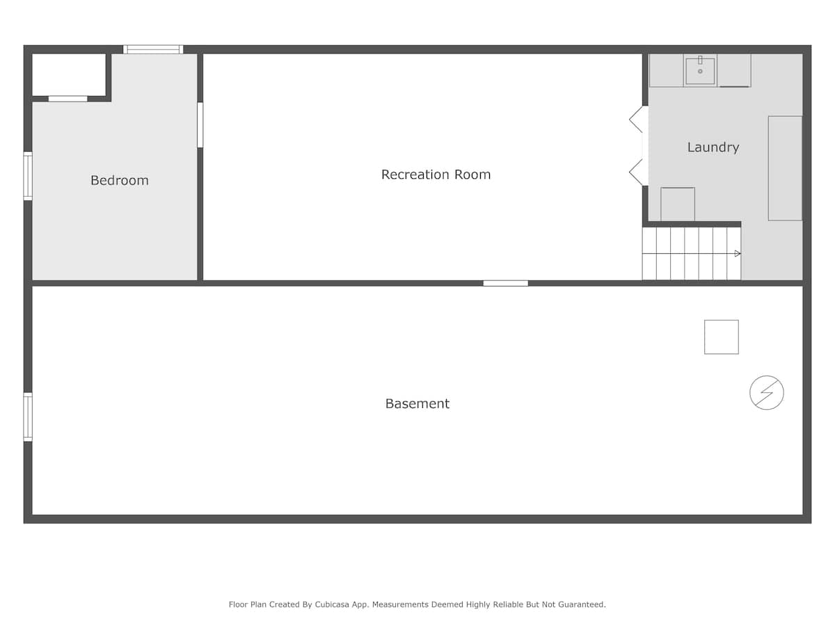 A detailed floor plan of a basement level, featuring a bedroom, a recreation room, a laundry area with a sink, and a large open basement space, indicating the layout and flow of the lower level.