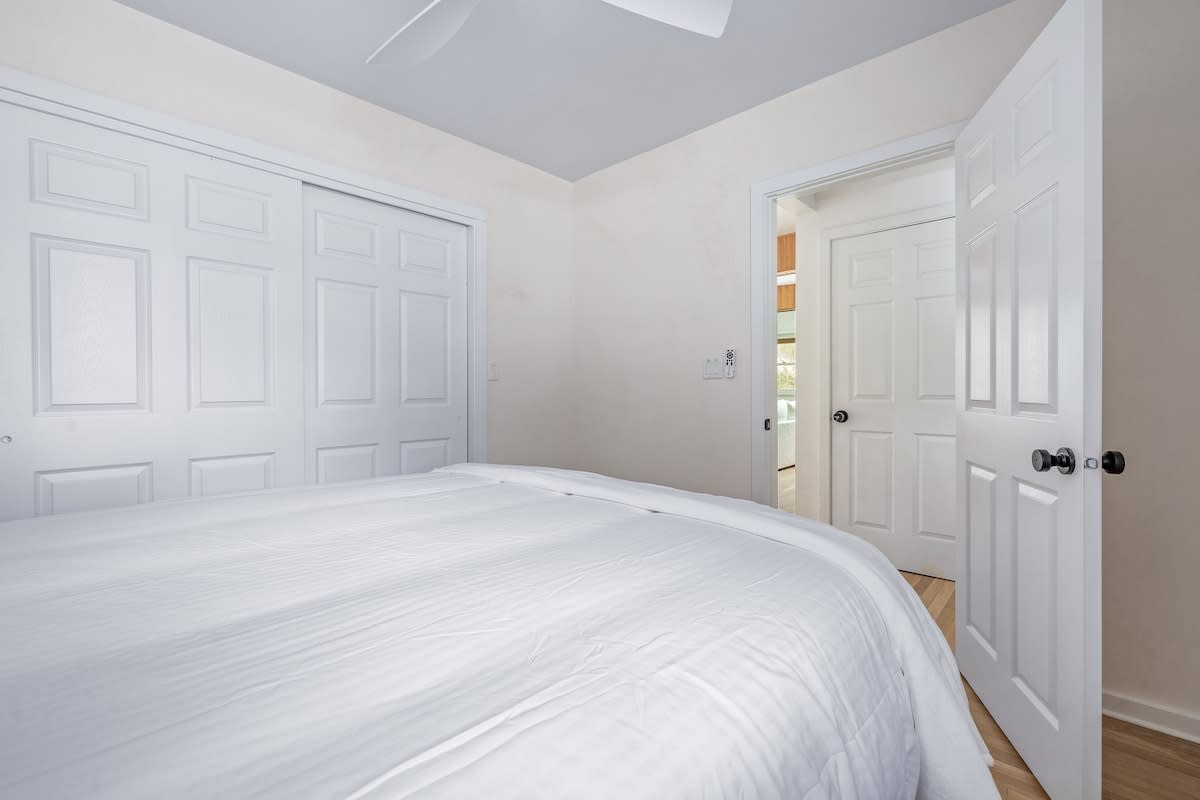 A closer look at the white bi-fold closet doors in the bedroom, with an open doorway revealing a glimpse of an adjacent room.