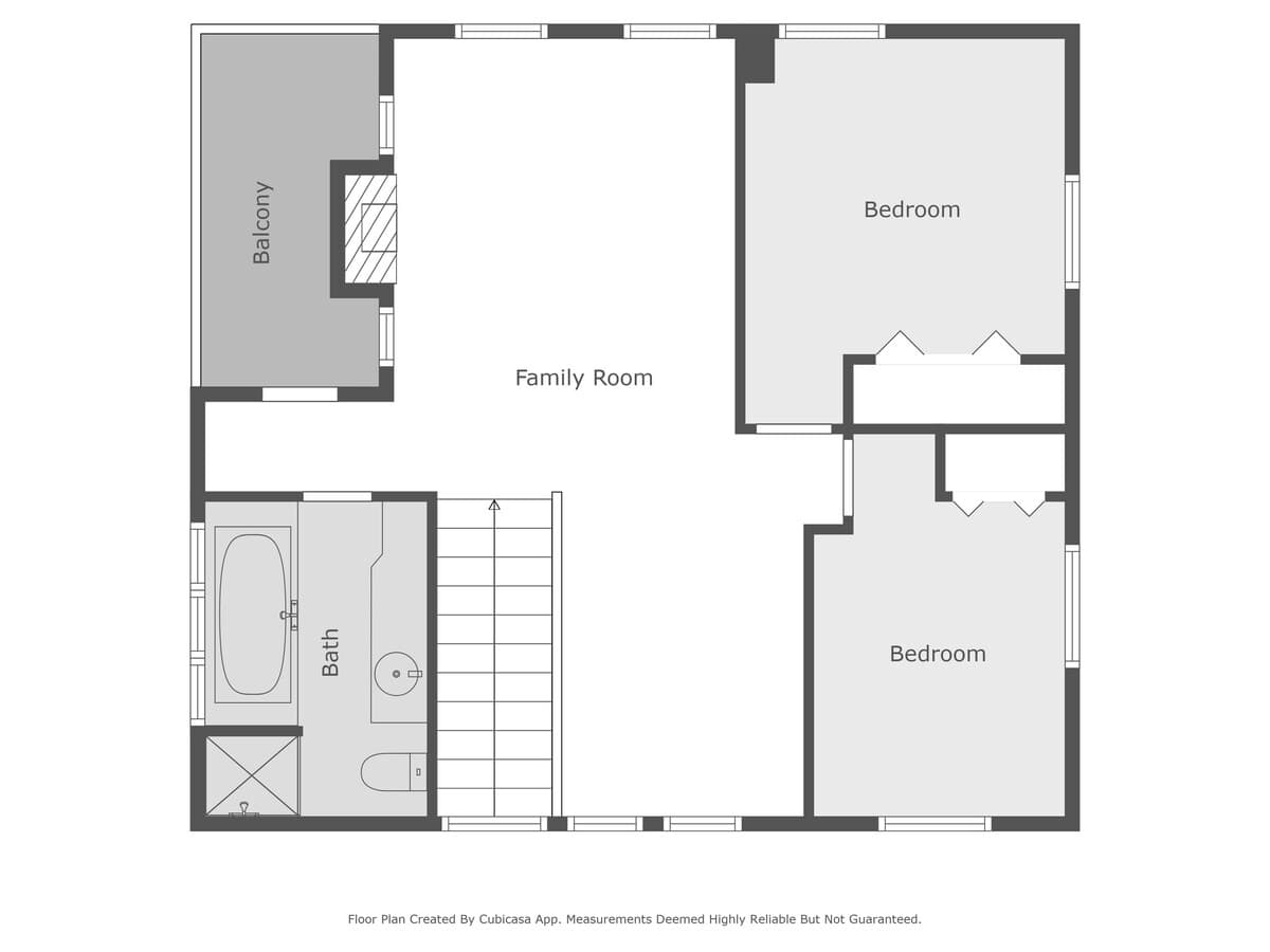 A detailed floor plan of the second level, featuring a family room, two bedrooms, a bathroom with a bathtub, a balcony, and stairs, with room labels and basic fixtures.