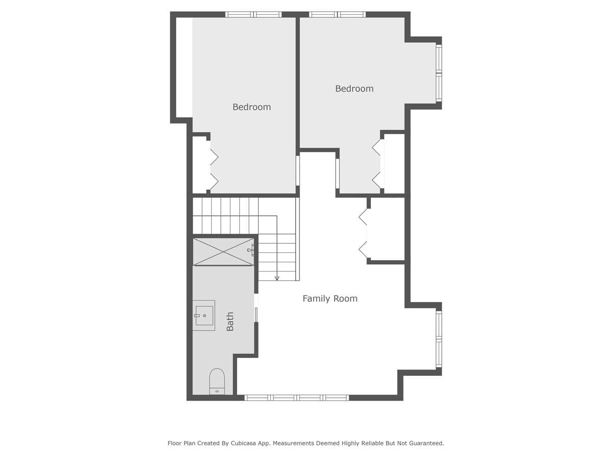 A top-down floor plan of the second floor, illustrating the layout with two bedrooms, a family room, and a bathroom, connected by a central staircase.
