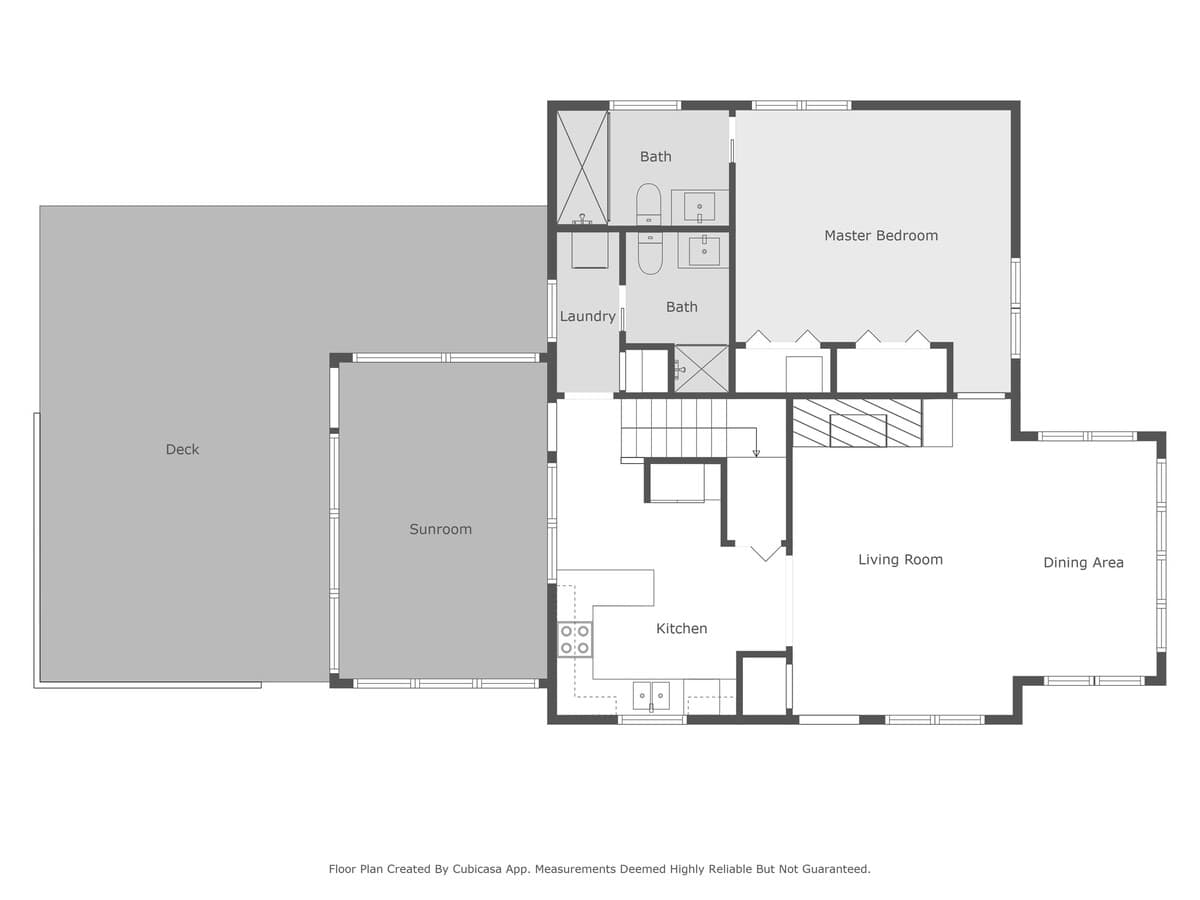 A detailed top-down floor plan of the first floor, highlighting a kitchen, living room, dining area, master bedroom with two baths, a laundry room, sunroom, and an expansive outdoor deck.