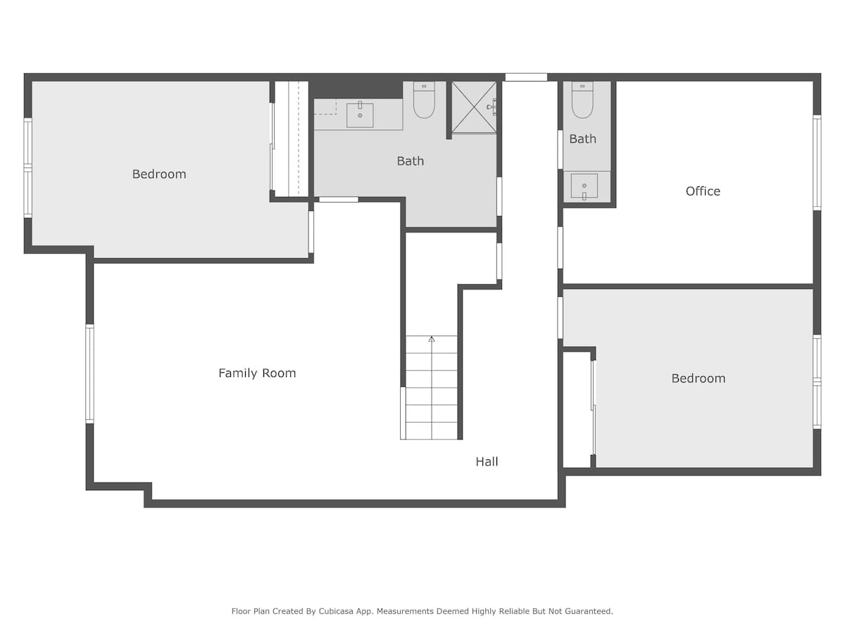 A detailed floor plan of the lower level, featuring a spacious family room, an office, two bedrooms, a central hall, and two bathrooms, accessible via a staircase.