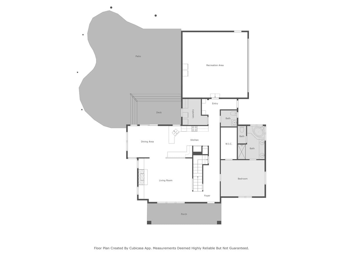 A detailed floor plan of the ground level, illustrating the layout of the living room, kitchen, dining area, a bedroom, multiple bathrooms, a recreation area, deck, patio, and front porch.