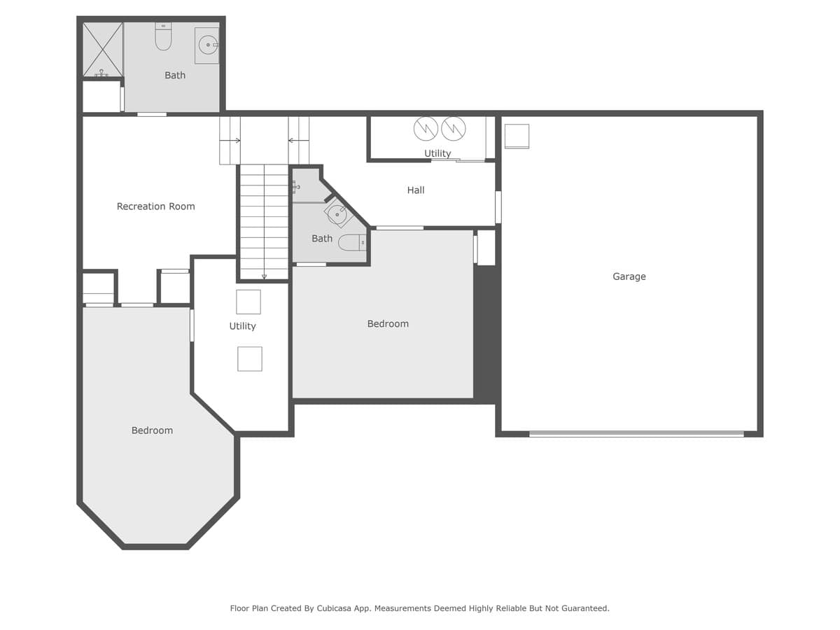 Detailed floor plan of the lower level, showcasing a recreation room, two bedrooms, bathrooms, utility areas, and an integrated garage, with internal stair access to upper floors.