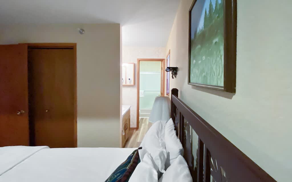 A view from bedroom 1 towards an open doorway revealing a bathroom with a vanity and mirror, highlighting the ensuite convenience, with a closet door visible to the left.