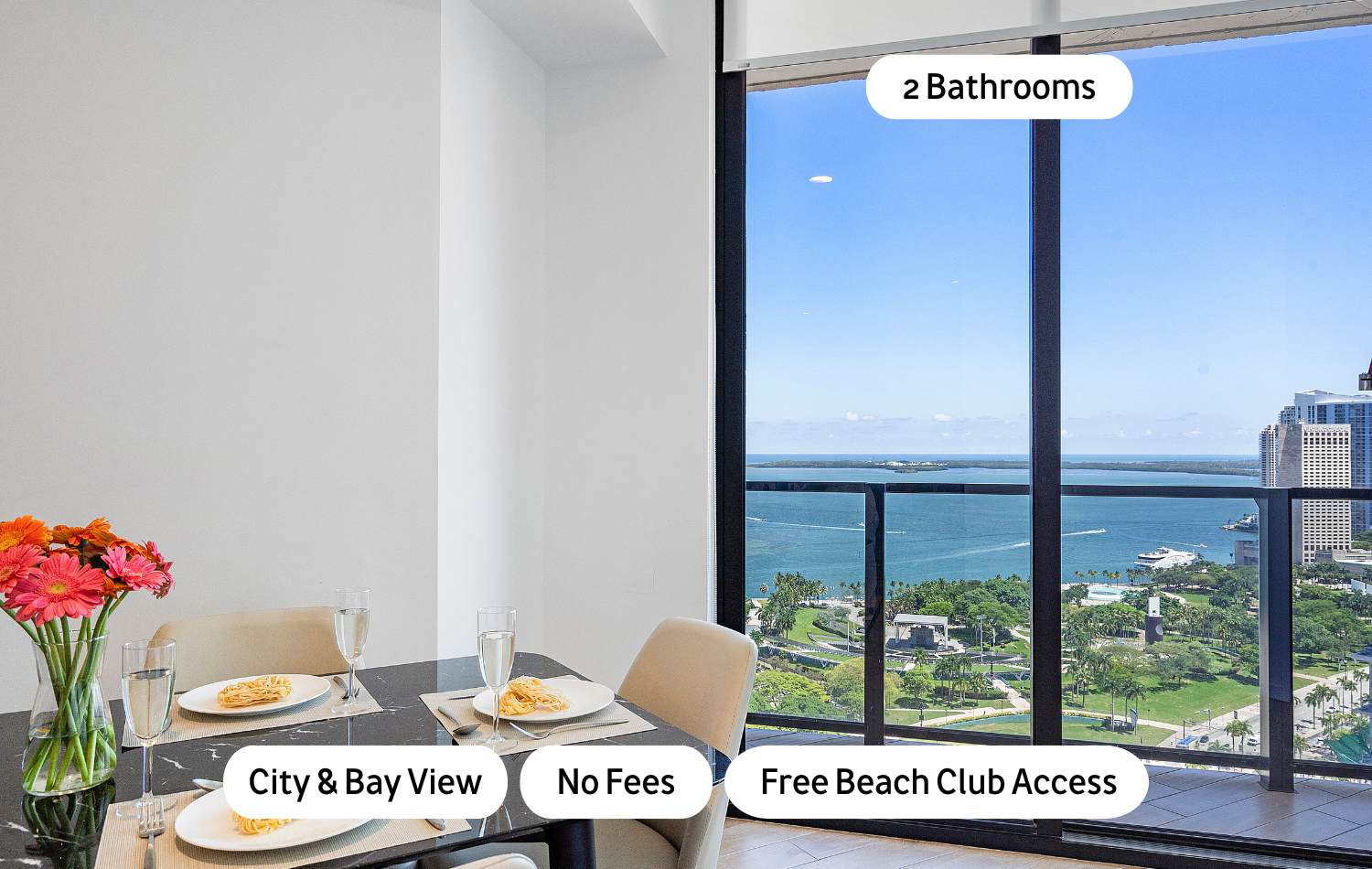 Modern dining area featuring a dark marble-top table set for four, with light upholstered chairs, and a stunning bay and city view through floor-to-ceiling windows.