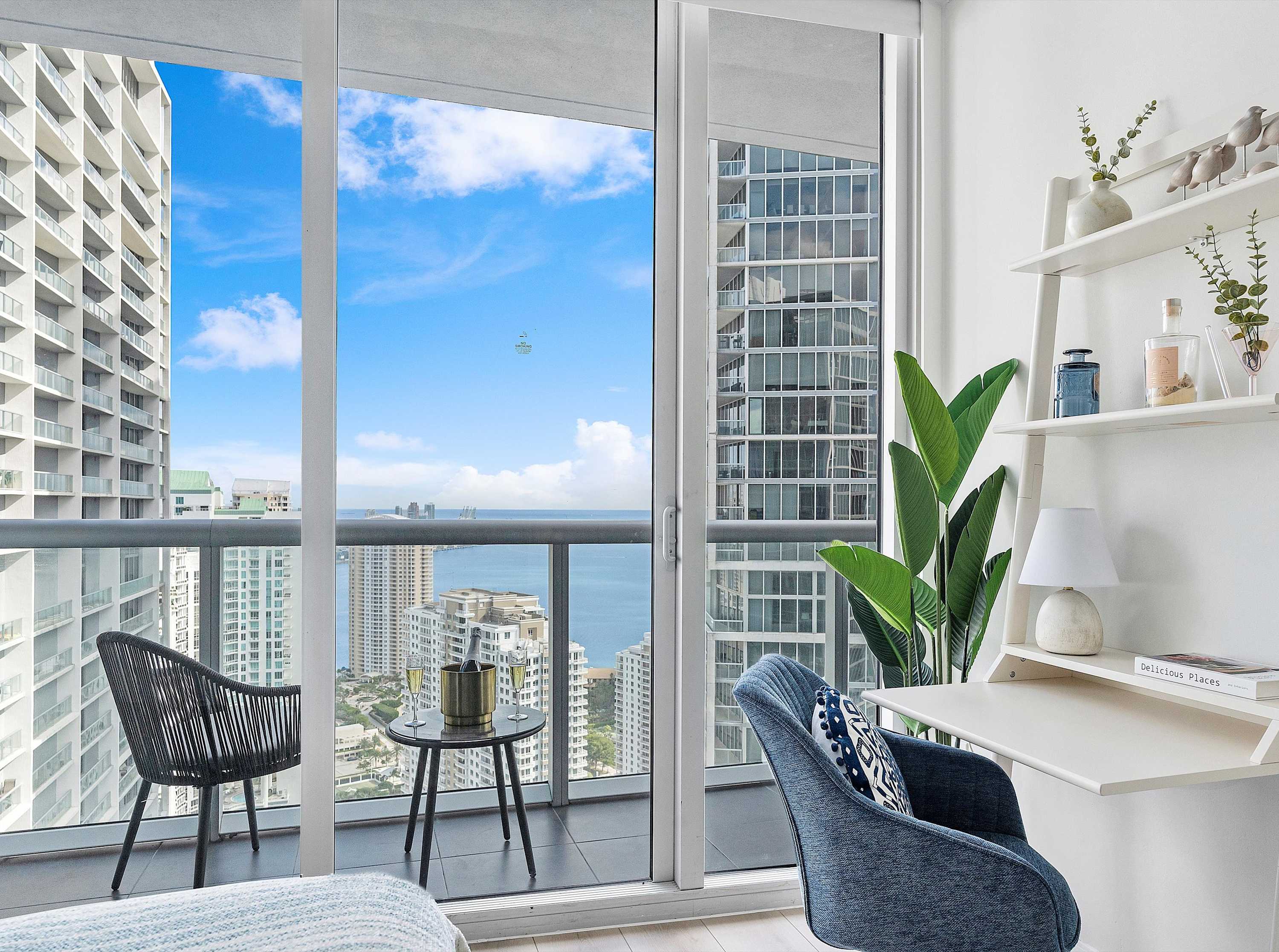 Private balcony accessible from the second bedroom, furnished with outdoor seating and a small table, offering expansive views of the city skyline and bay.