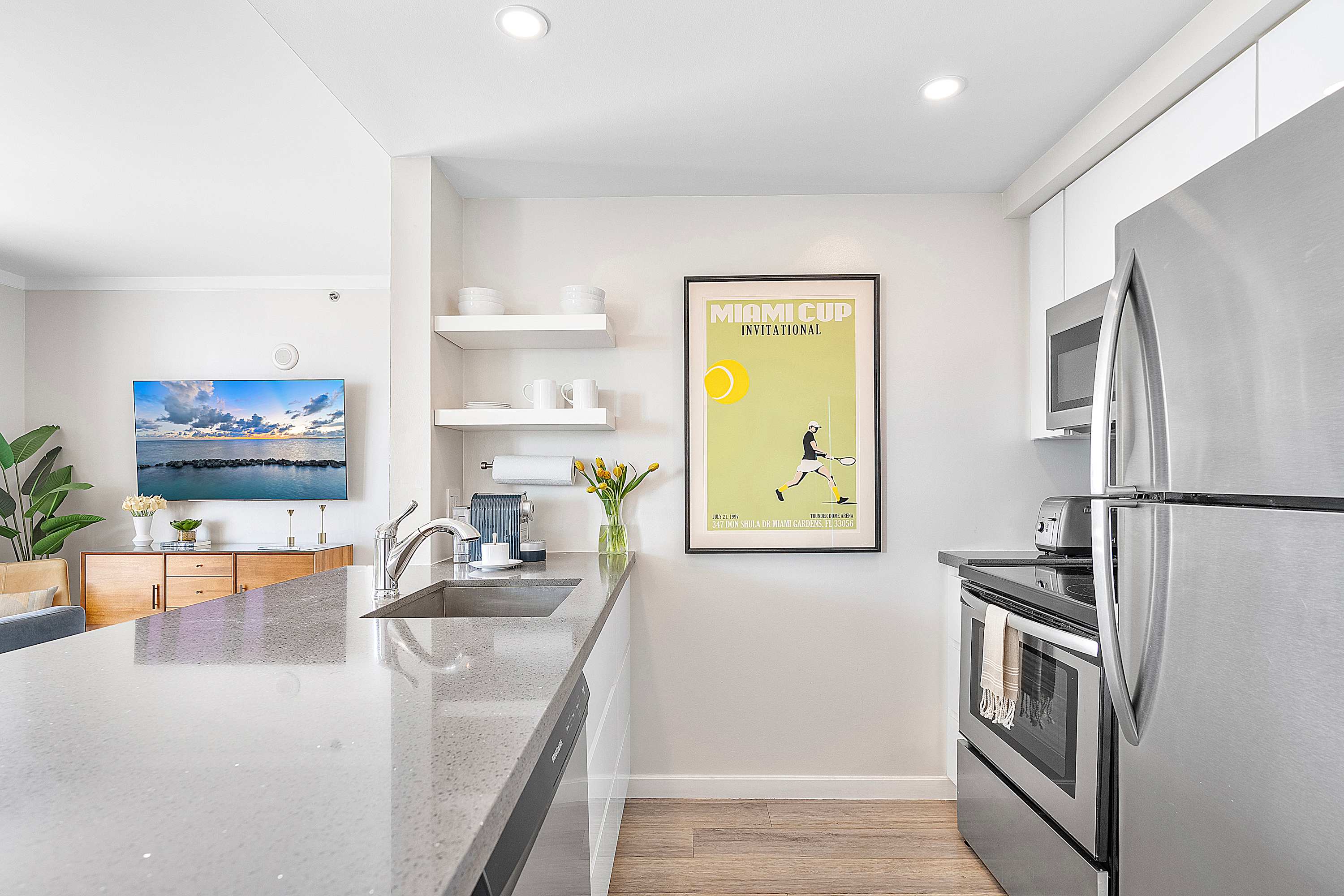 Modern kitchen with light gray countertops, white cabinetry, stainless steel appliances including a refrigerator and stove, and open shelving above the sink area.