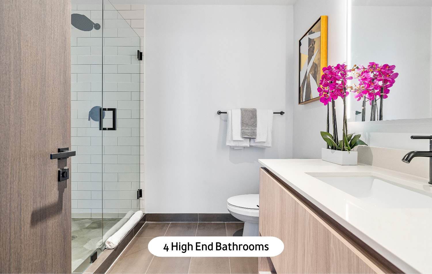 A high-end, modern bathroom featuring a spacious walk-in shower with a glass enclosure, a single vanity with a white countertop and dark wood-grain cabinet, and a toilet, all in a clean, minimalist design.