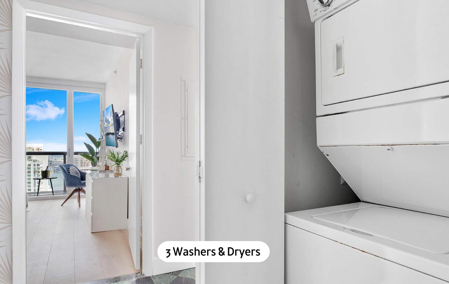 A dedicated laundry area featuring stacked white washer and dryer units, situated in a bright space with a doorway leading to another room that boasts large windows and a view.