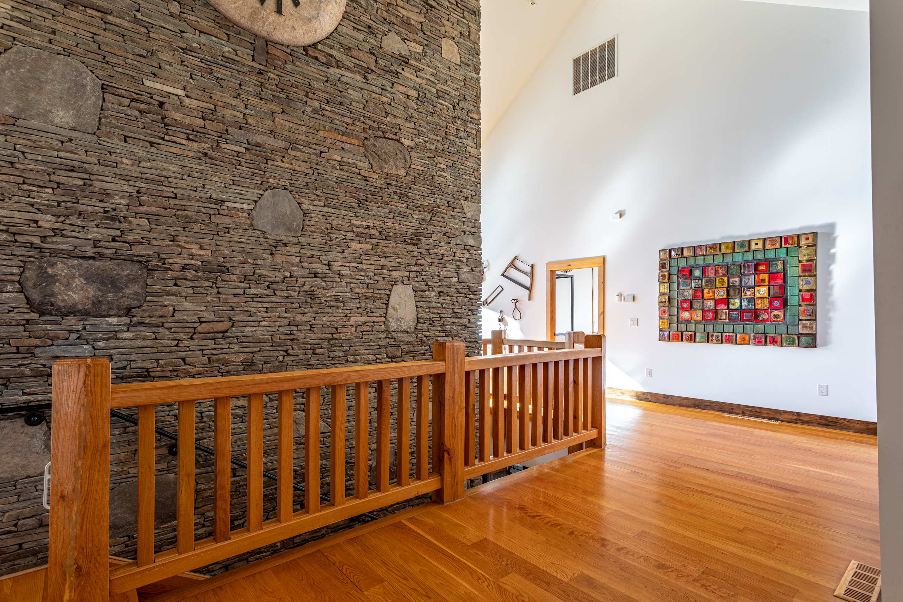 Close-up of the impressive stone wall, featuring various rustic tools and a decorative metal heart sculpture mounted on it, adding character to the entryway.