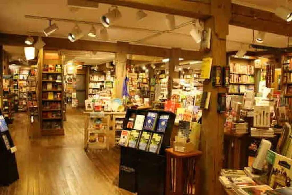 Cozy and expansive bookstore interior with numerous wooden shelves filled with books, warm lighting, and exposed wooden beams, creating an inviting atmosphere for browsing.