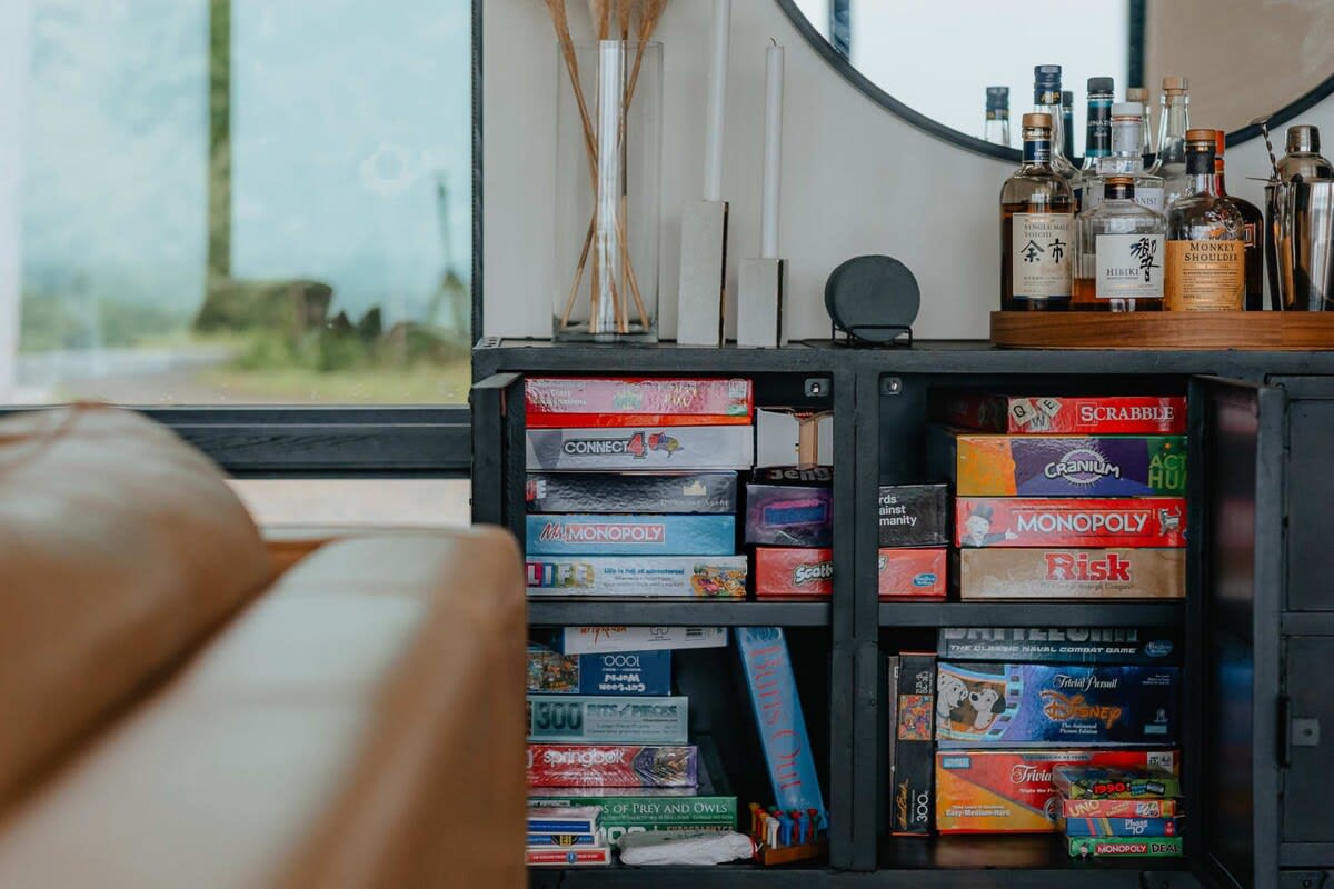 The open doors of a black metal cabinet reveal shelves packed with various board games like Monopoly, Scrabble, and Risk, indicating a dedicated entertainment or game storage area.