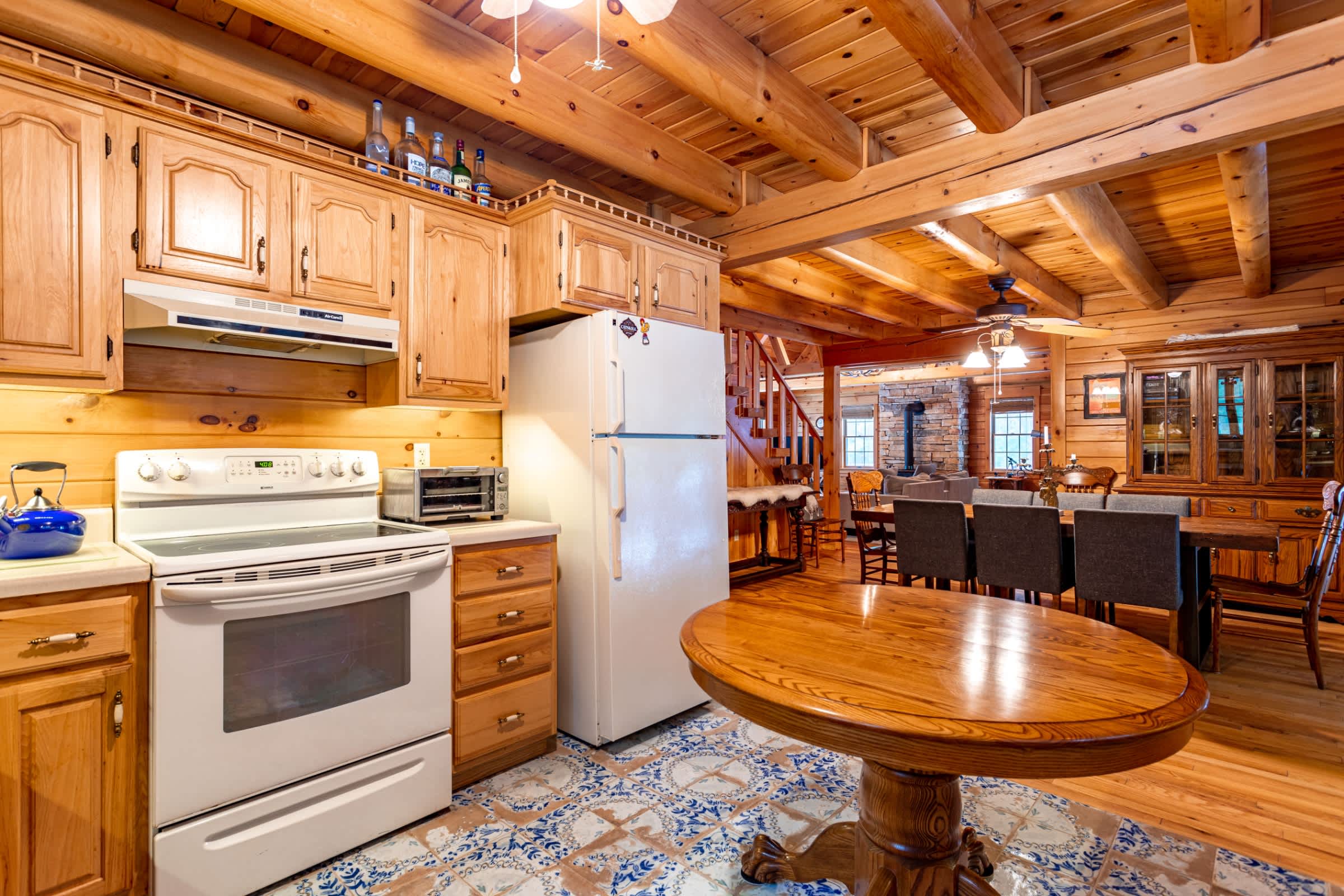 A detailed shot of the kitchen counter area showcases a coffee maker, espresso machine, and knife block on a light countertop. Light wood cabinets and a wood-paneled backsplash are visible.