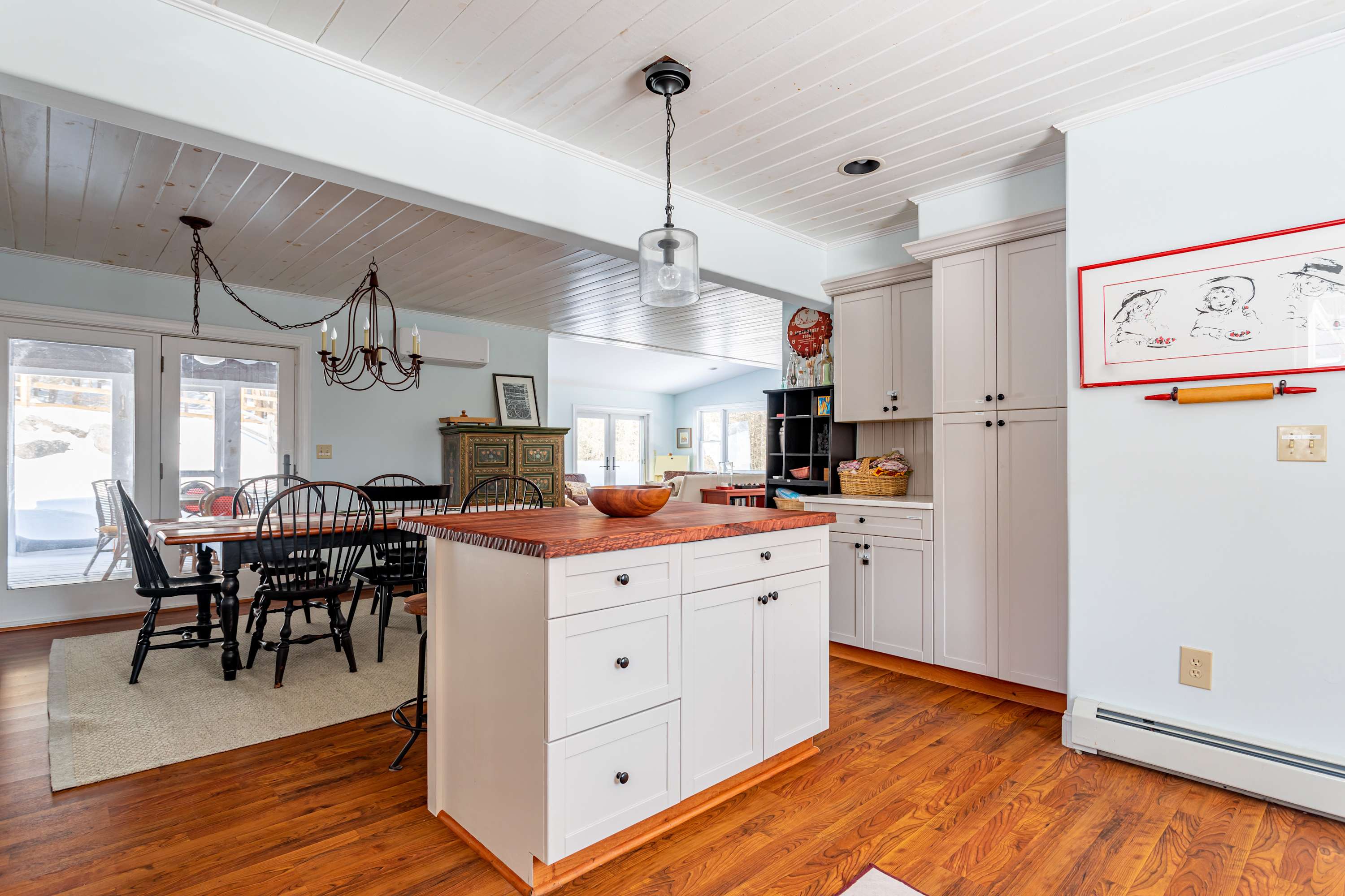 Another angle of the kitchen, showing the island with a wooden countertop, white cabinets, and a view towards the dining area, highlighting the seamless flow between spaces.