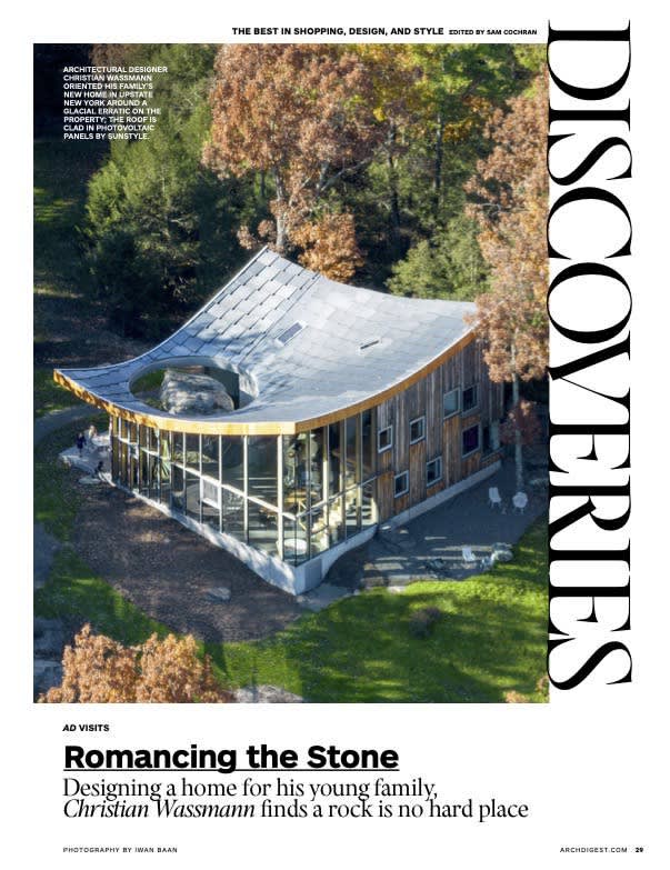 A magazine spread featuring an aerial view of a modern house with a distinctive curved roof and extensive glass walls, set amidst a lush green forest with autumn-colored trees. Architectural Digest branding is visible.