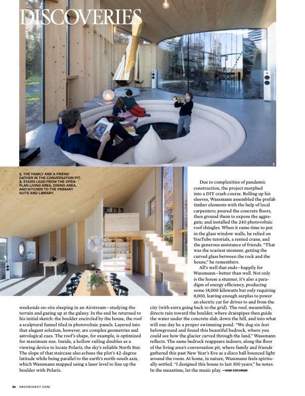 A magazine spread highlighting the open-concept living area with a custom-built curved sofa, large floor-to-ceiling windows offering forest views, and a dining space, all under a high, wood-paneled ceiling.