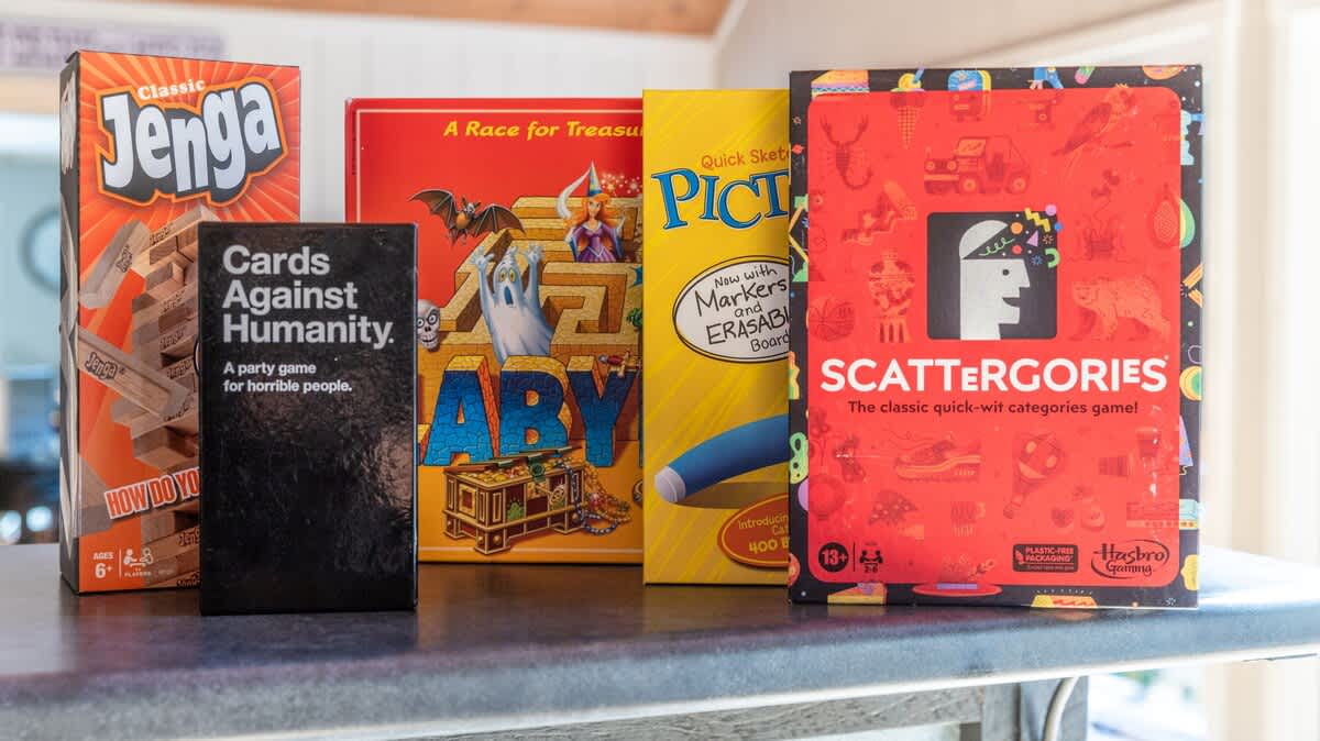 A collection of popular board games including Jenga, Cards Against Humanity, Labyrinth, Pictionary, and Scattergories, neatly arranged on a countertop, ready for family fun.