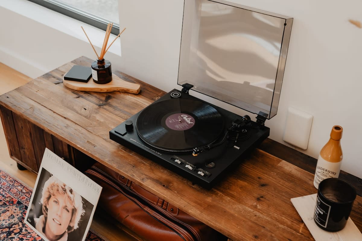 A close-up shot captures a vintage-style record player resting on a rustic wooden console table, accompanied by a classic record album and other decorative elements, adding a touch of nostalgia to the living space.