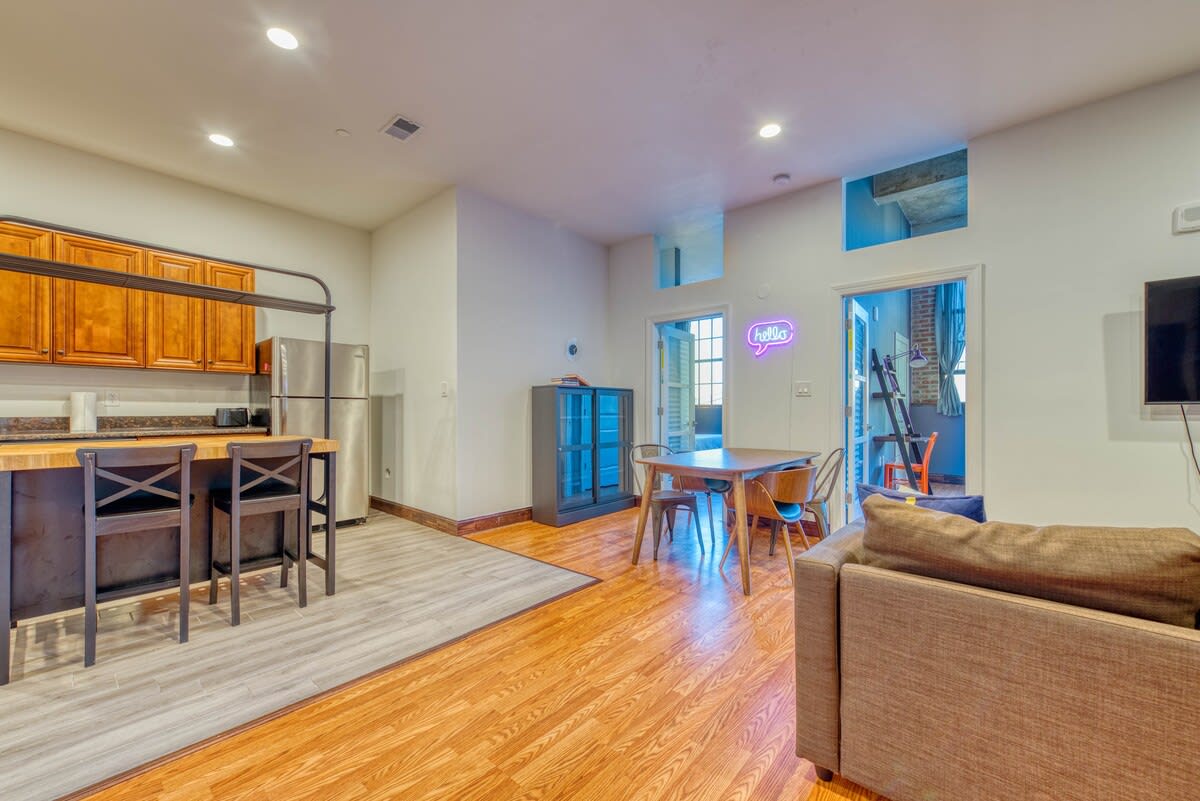 View of the open-concept living and dining area from the kitchen, showing a brown sectional sofa, dining table, and a kitchen island with two bar stools.