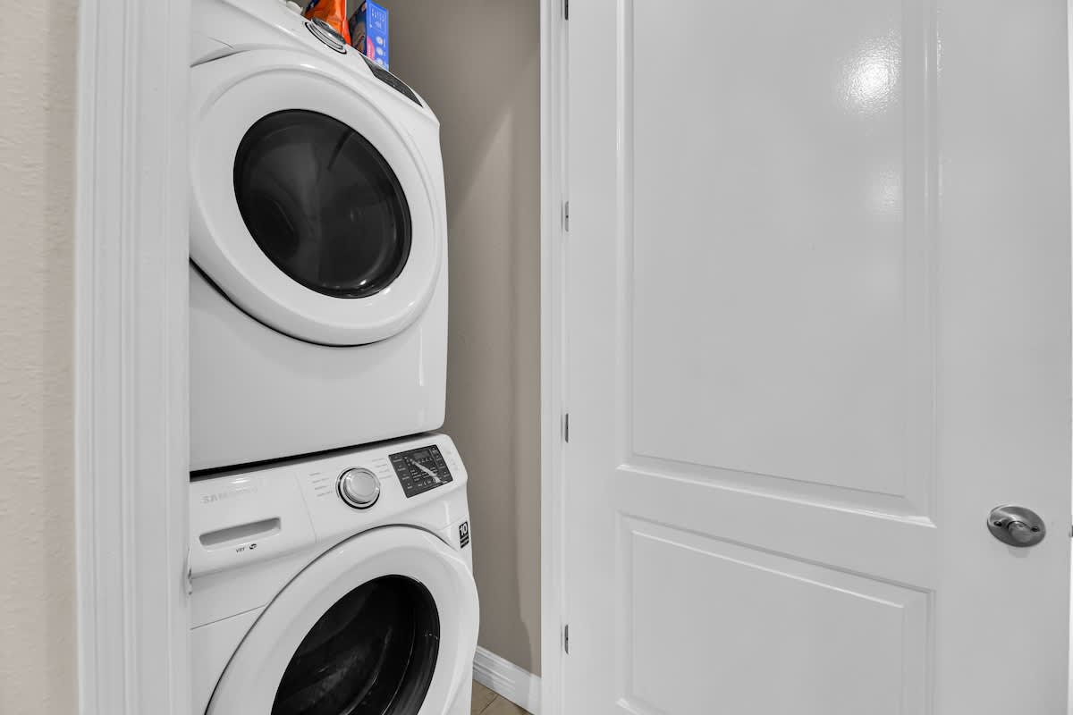 Compact laundry closet featuring a stacked white washer and dryer unit, neatly tucked away behind a white door, indicating convenient in-unit laundry facilities.