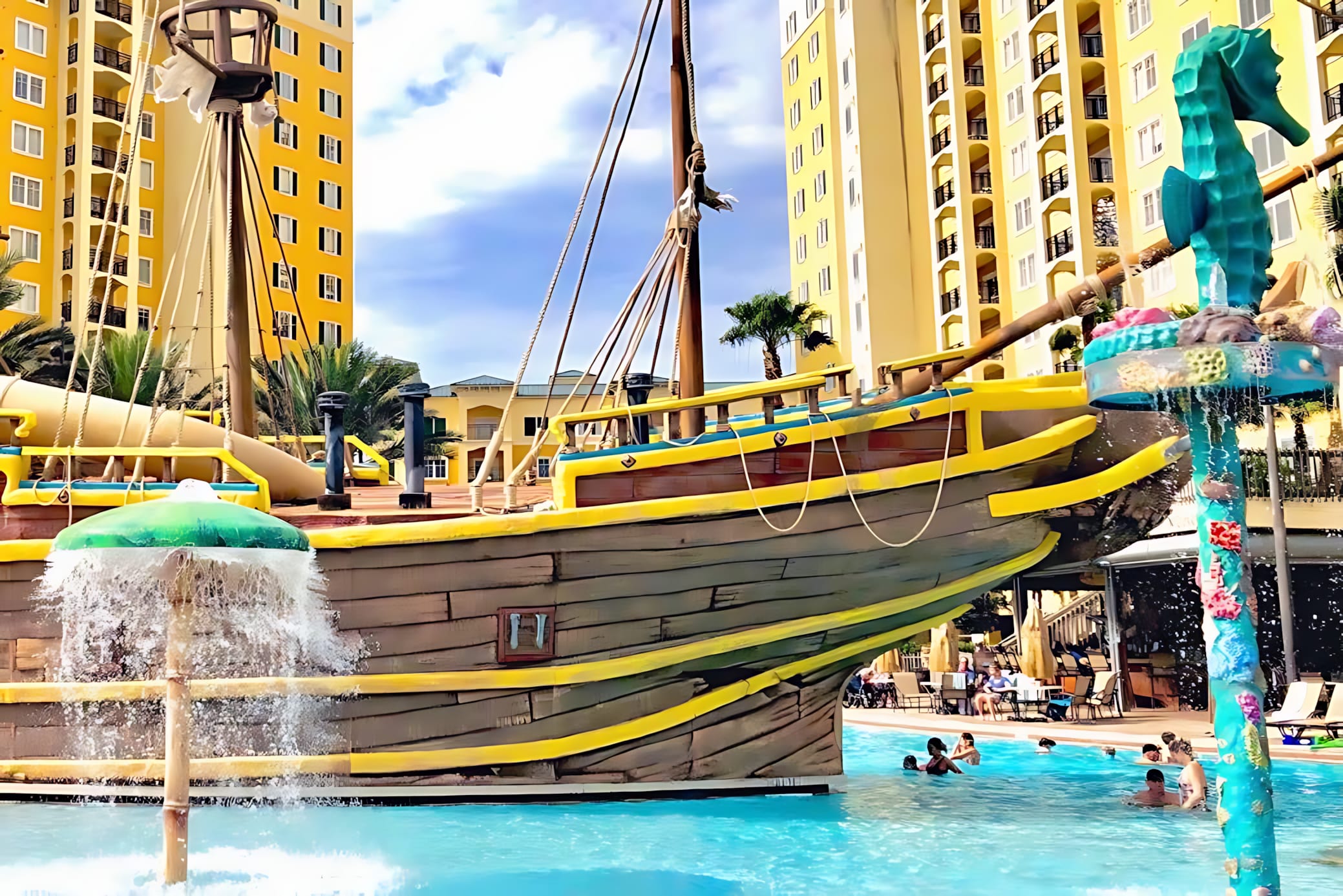 Vibrant communal pool area with a large pirate ship water play structure and a seahorse-themed water slide, set against a backdrop of multi-story resort buildings.